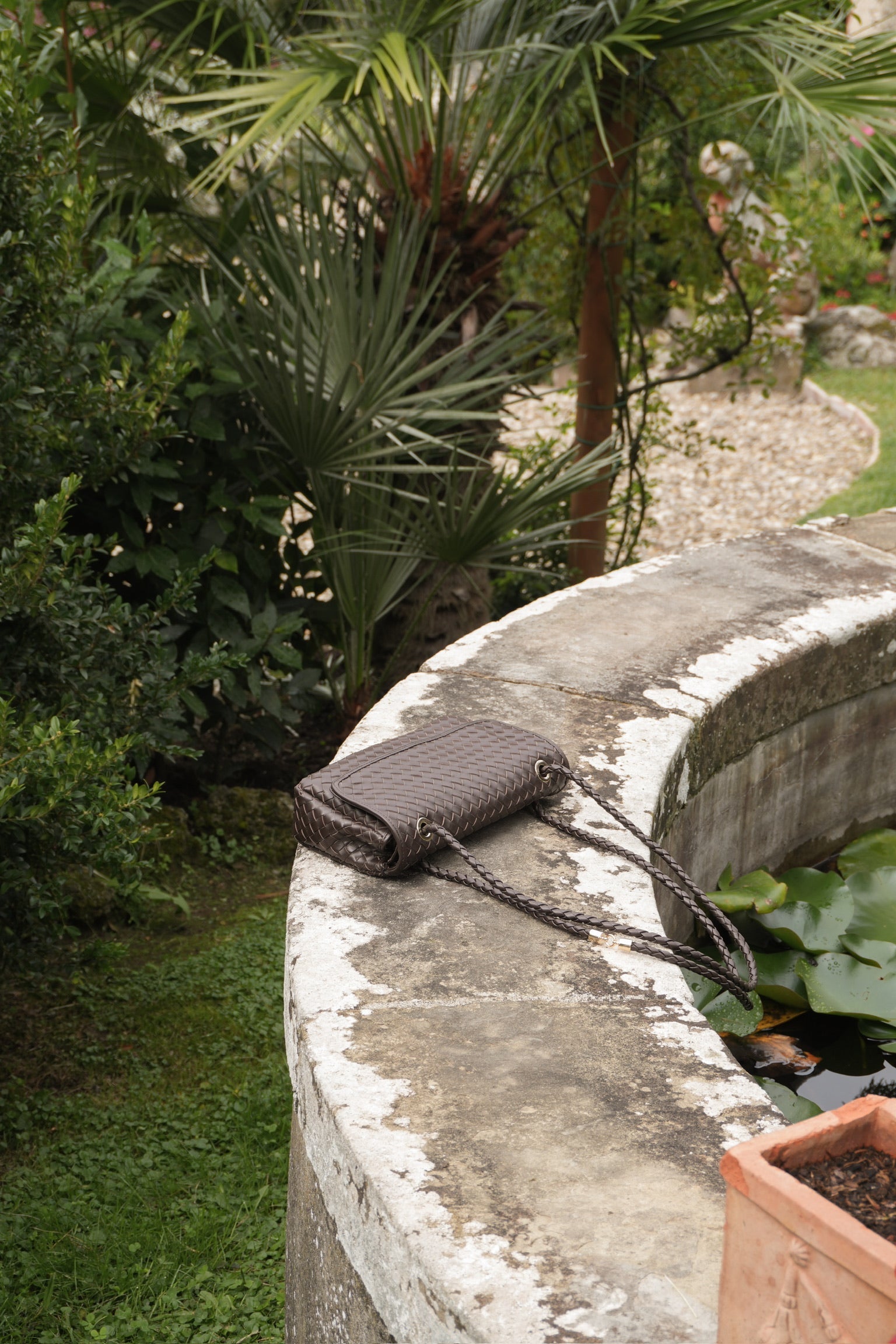 Ribichini Envelope-veske i flettet skinn, elegant plassert i italiensk hage – håndlaget tidløs luksus.