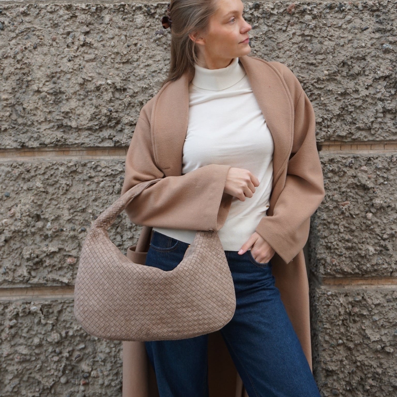 Kvinne med Ribichini Isola Royal i semsket terra – håndflettet italiensk skinnveske båret over armen.