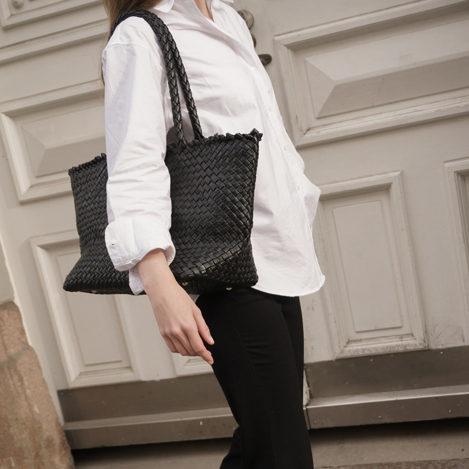 Kvinne bærer Ribichini Woodstock classic i sort flettet skinn – håndlaget italiensk veske.