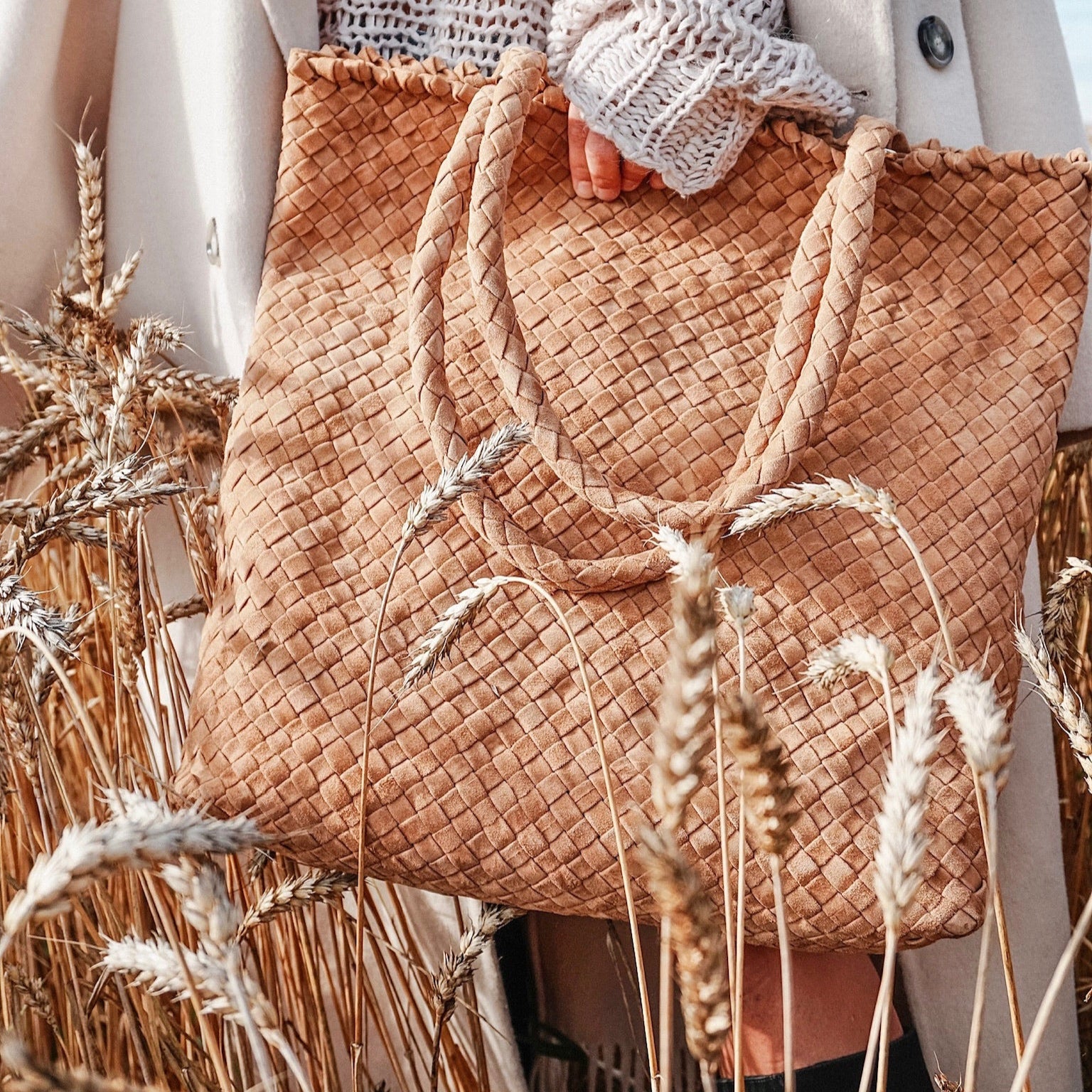 Ribichini Woodstock Royal Camel – håndflettet veske i mykt kamelfarget skinn, stylet med strikk og ullkåpe i åkeren.