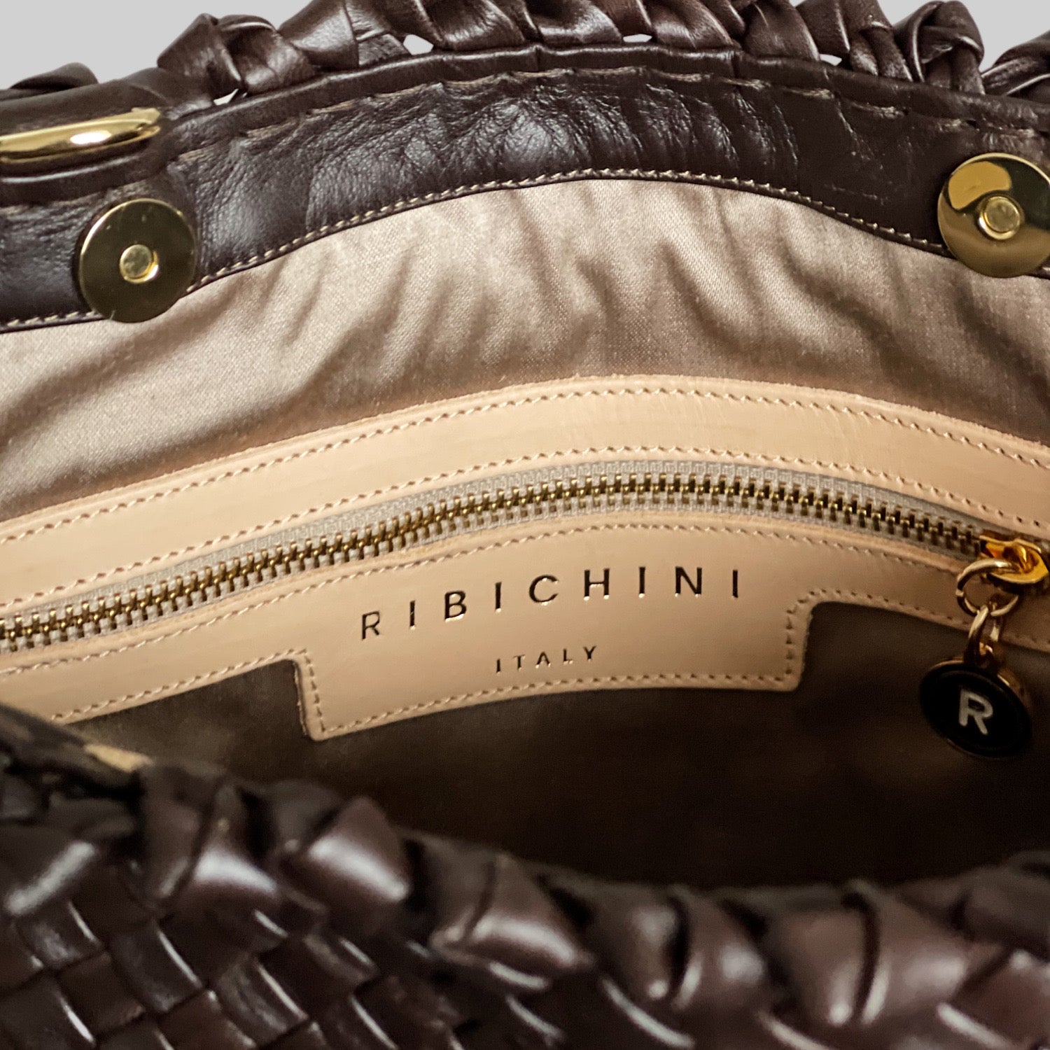 Ribichini Woodstock Babe i sjokoladefarge: Praktisk innside med gullfarget glidelås og R-logo. Velorganiserte lommer for enkel oppbevaring.