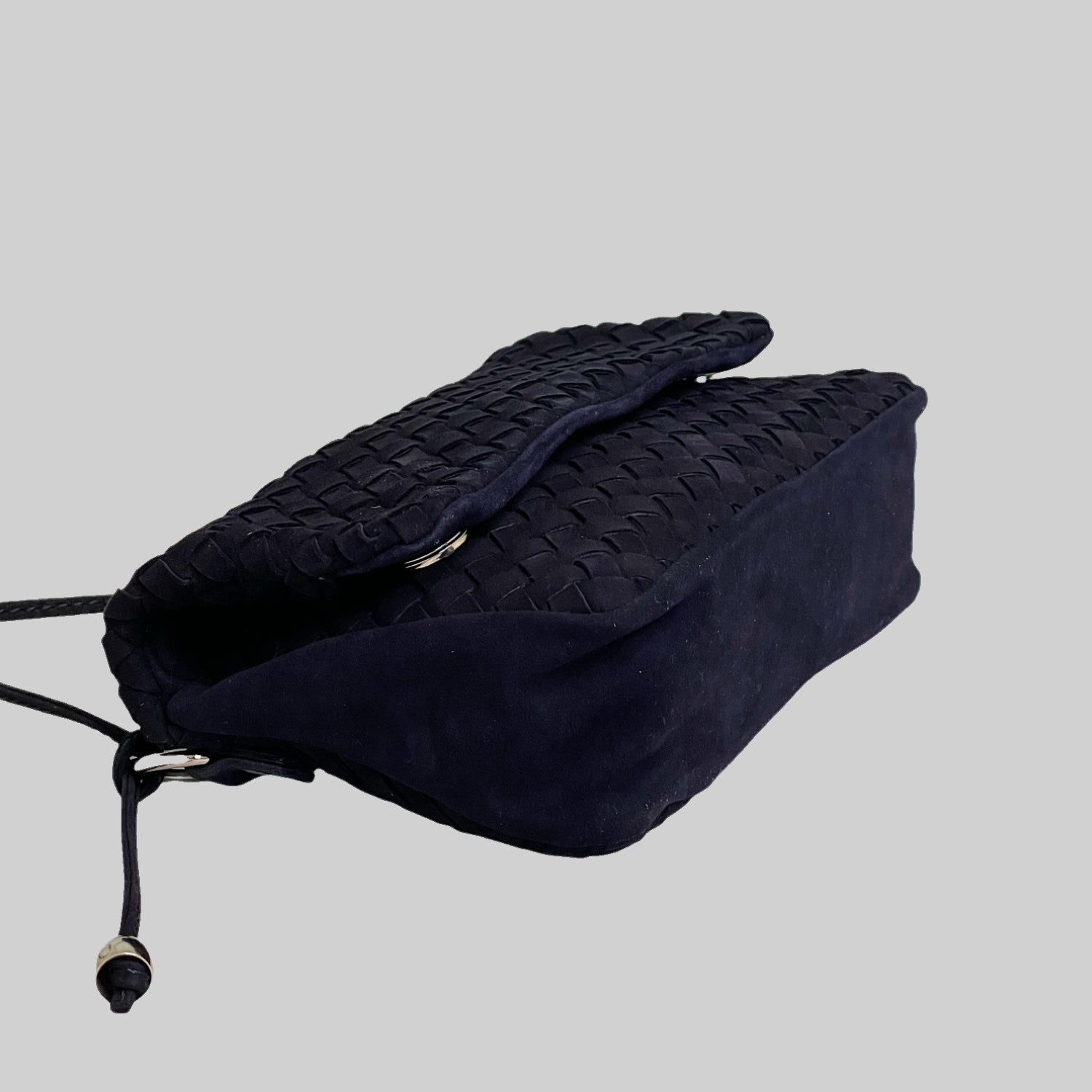 Ribichini Undercover i navy, en flettet semsket skinnveske, sett fra siden. Den kan brettes for en kompakt form, med magneter for lukking. Sølvdetaljer legger til stil.