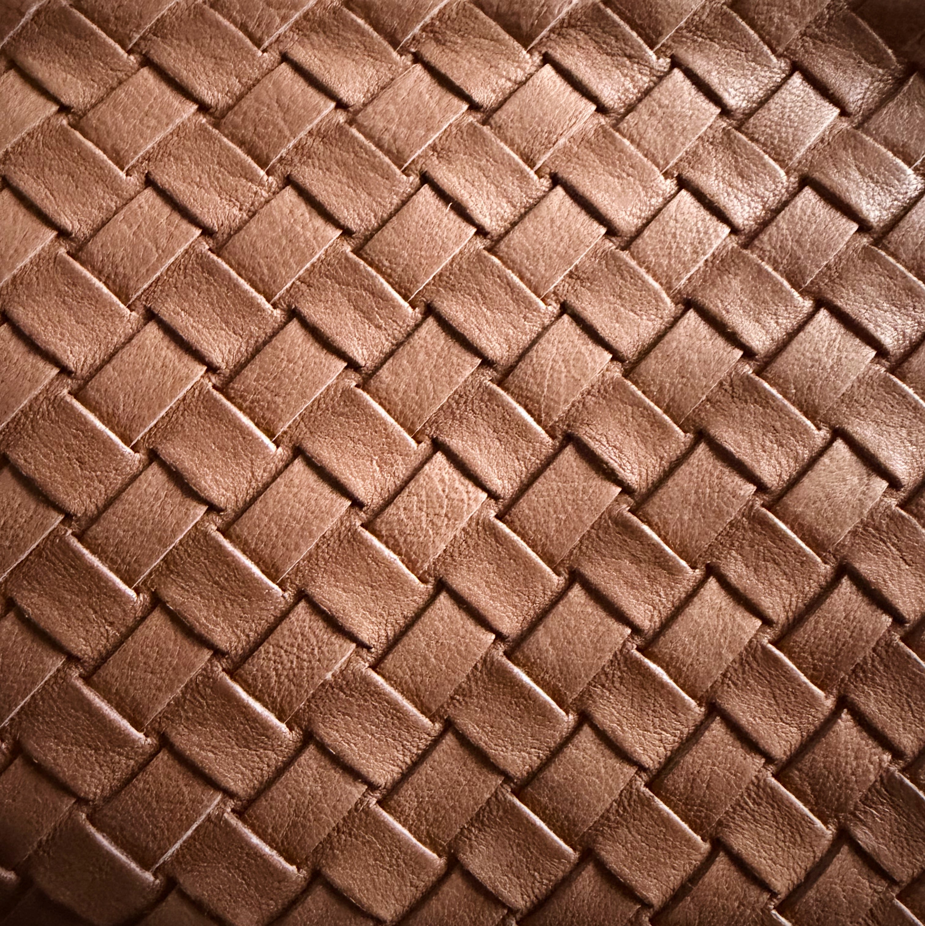 Eksklusivt nærbilde av Camper Clutch i cognac, håndflettet skinn med varm glans.