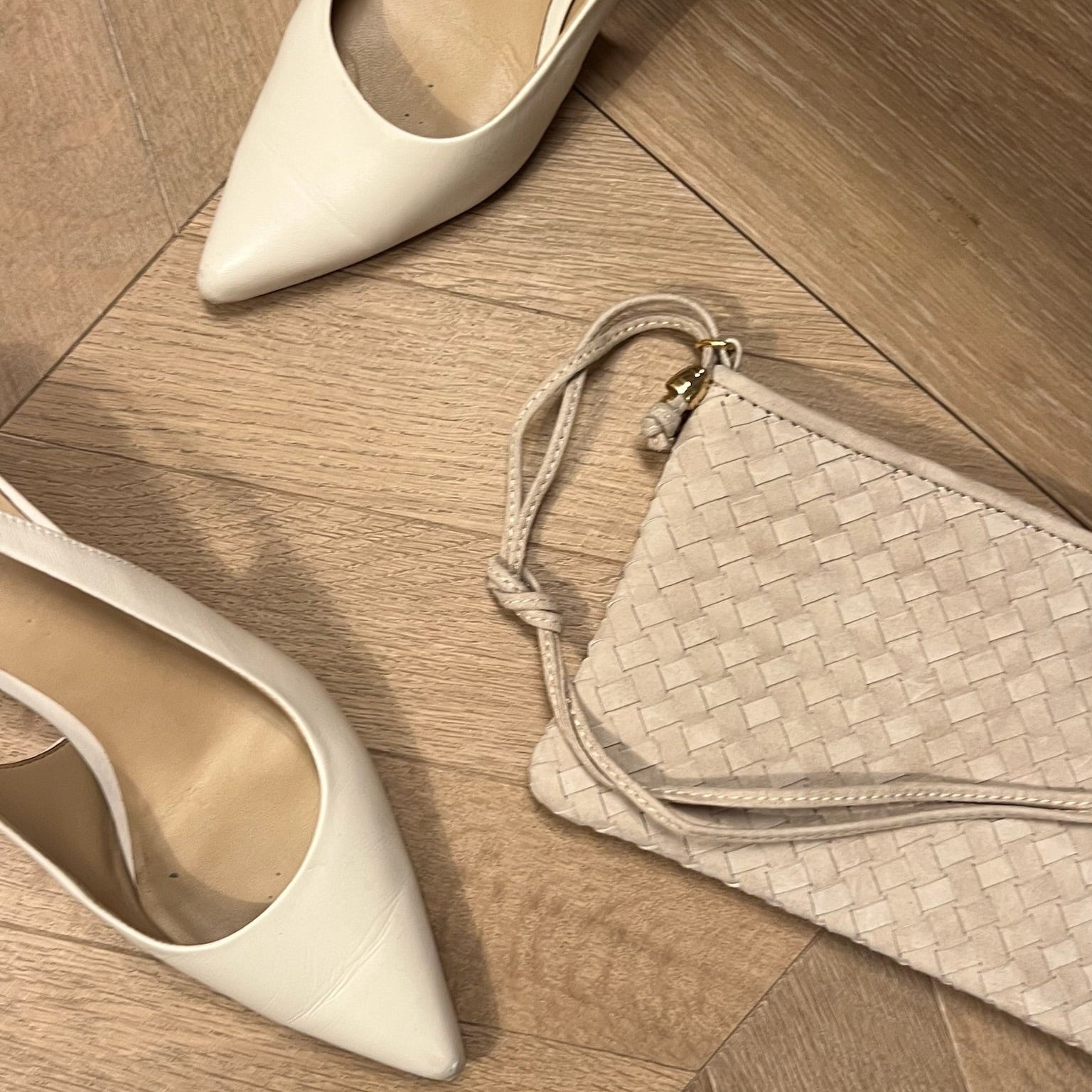 Ribichini Camper Clutch Sand håndlaget flettet skinnclutch i semsket lammeskinn sammen med lyse sko.