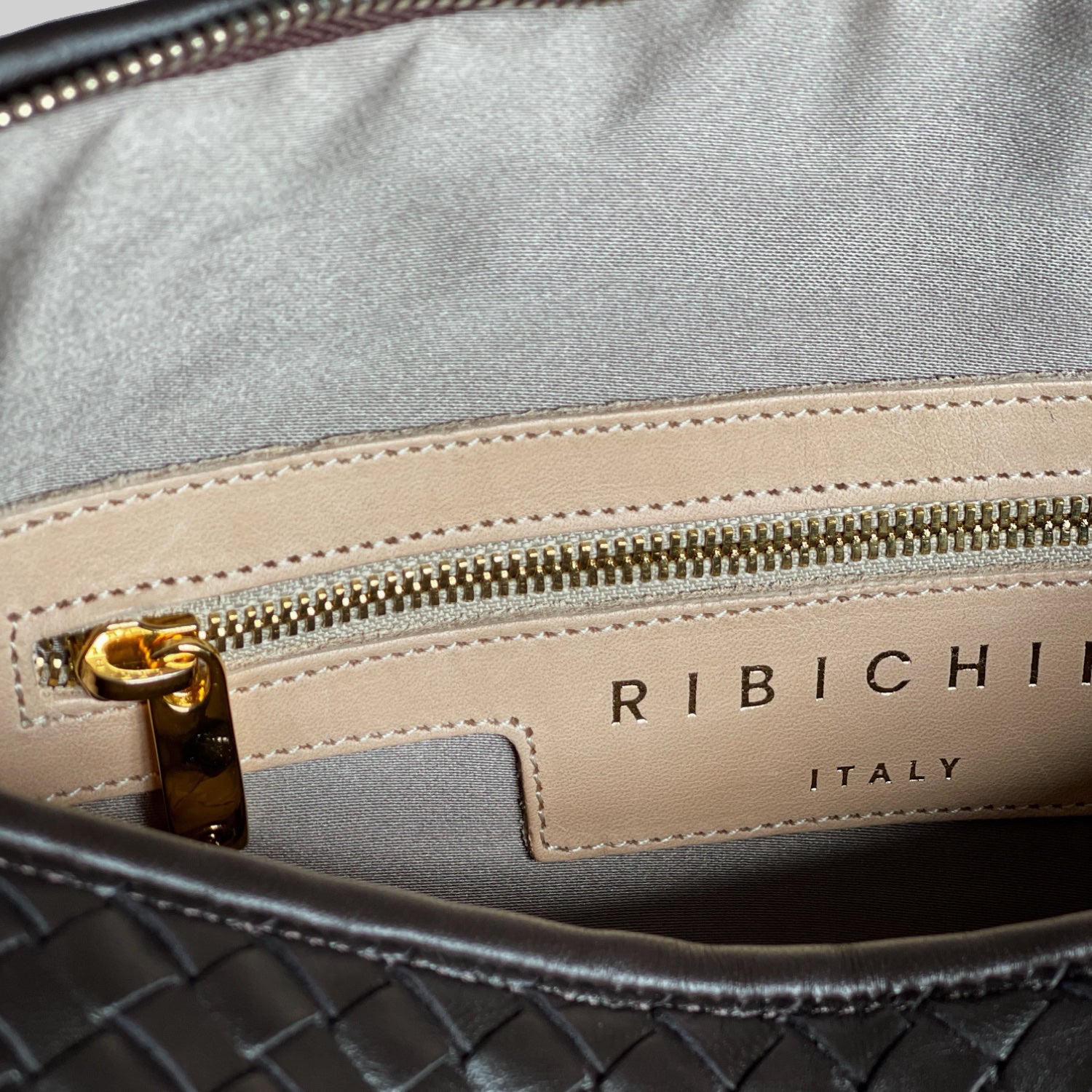 Interiør av Ribichini-veske viser merkelappen og en glidelåslomme, detaljer i gull