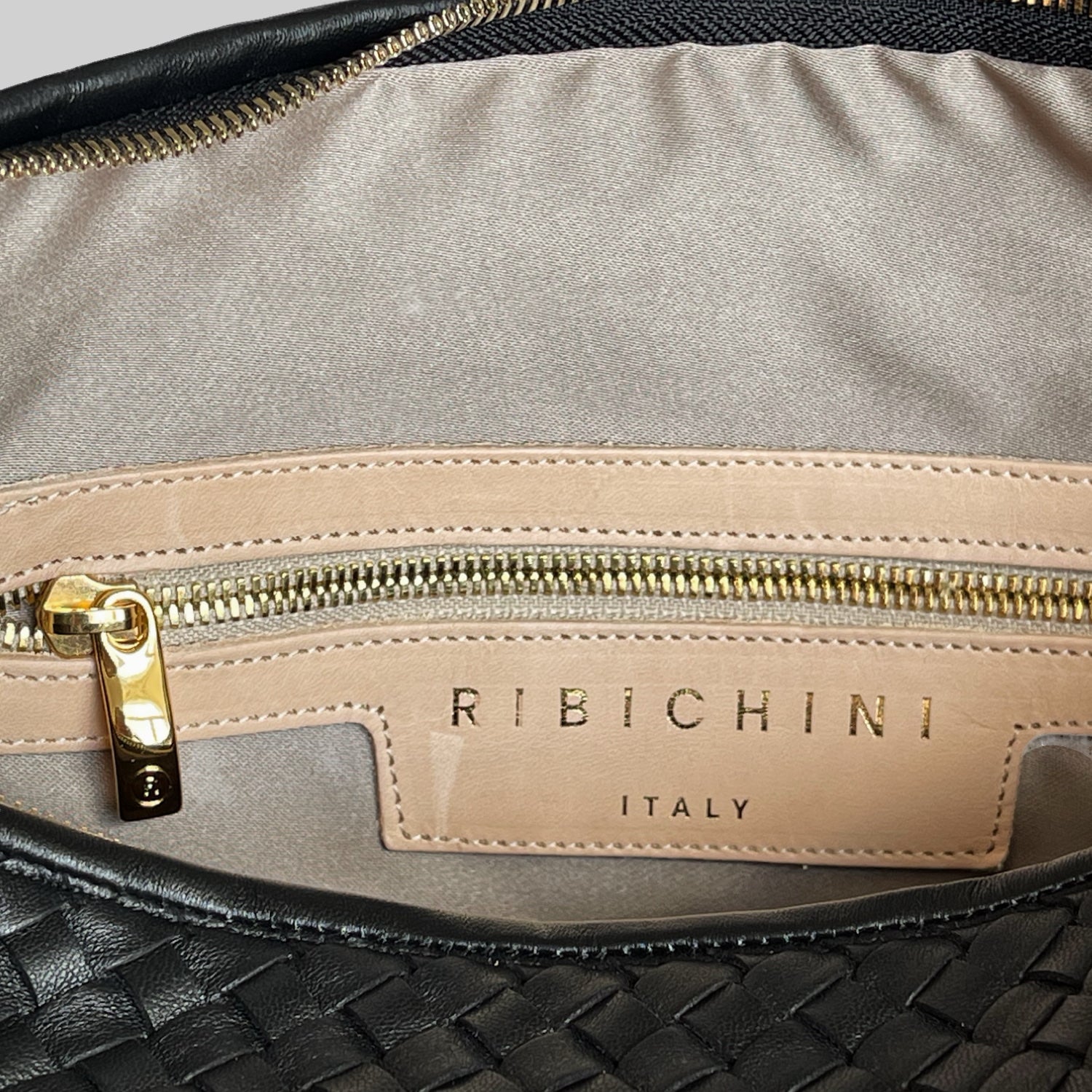 Interiør av Ribichini-veske viser merkelappen og en glidelåslomme, detaljer i gull