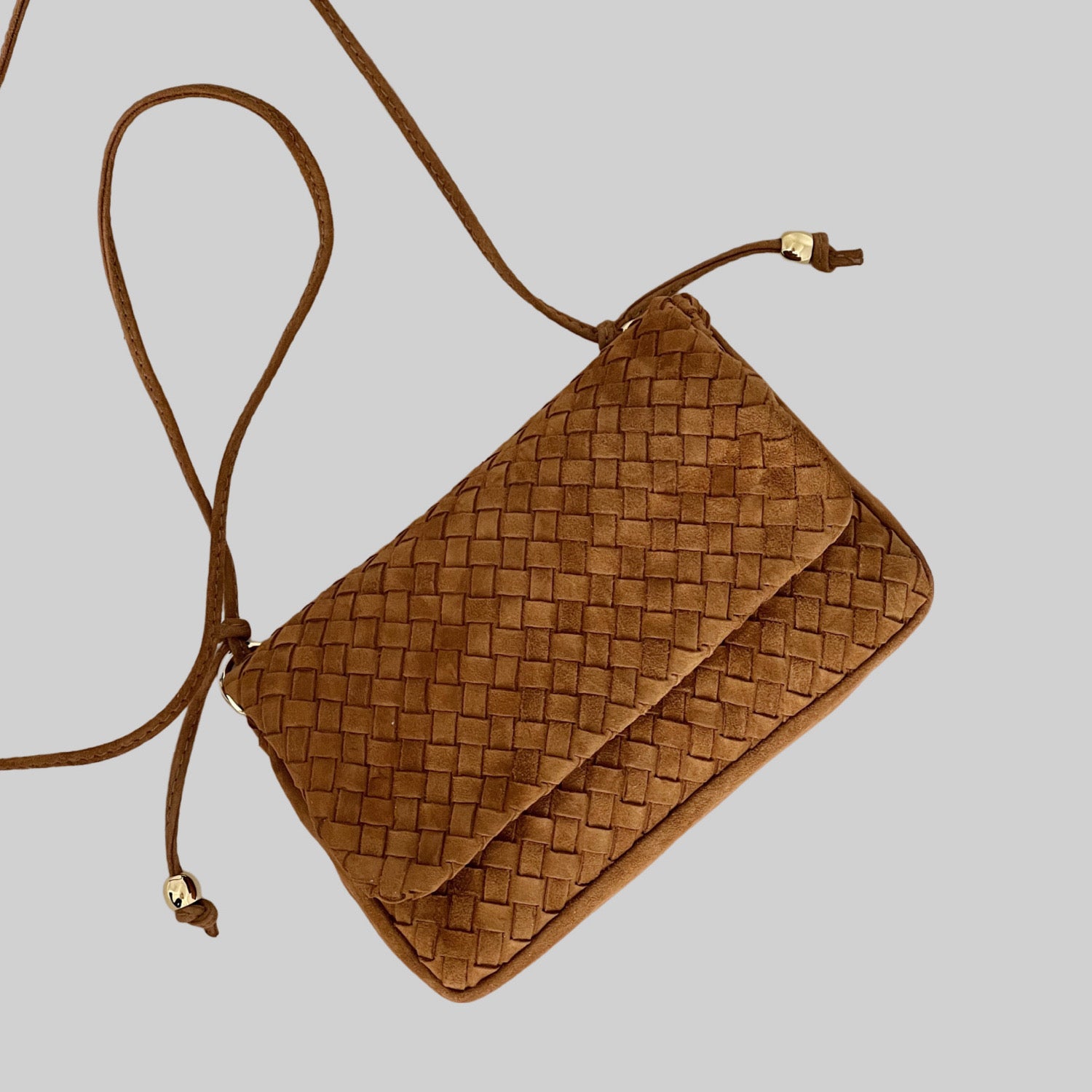 Ribichini Undercover i camel er en allsidig veske laget av semsket skinn. Den kan brettes for å bli kompakt og lukkes med magneter for sikkerhet.