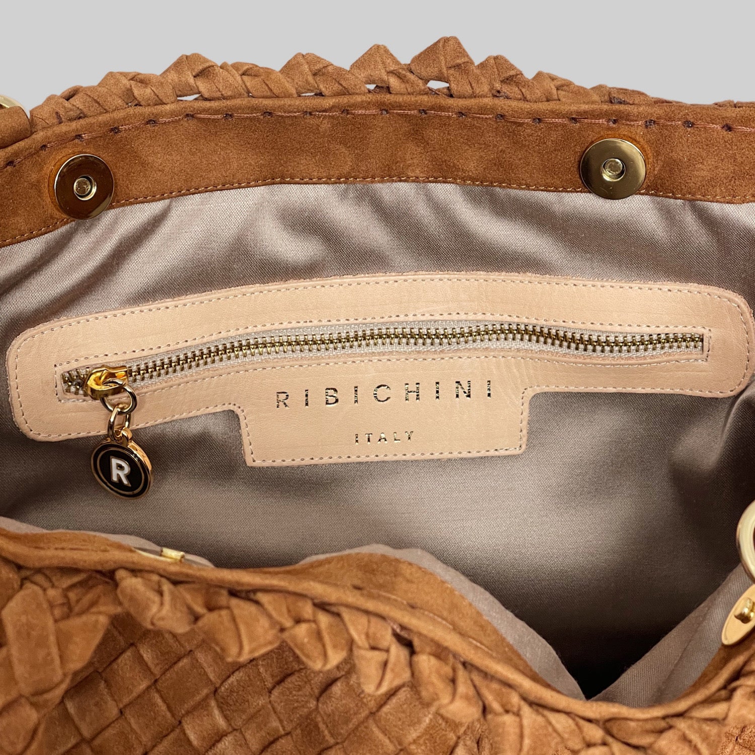 Innsiden av Ribichini Woodstock Royal veske i camel er organisert med gullfarget glidelås og ikonisk R-logo.