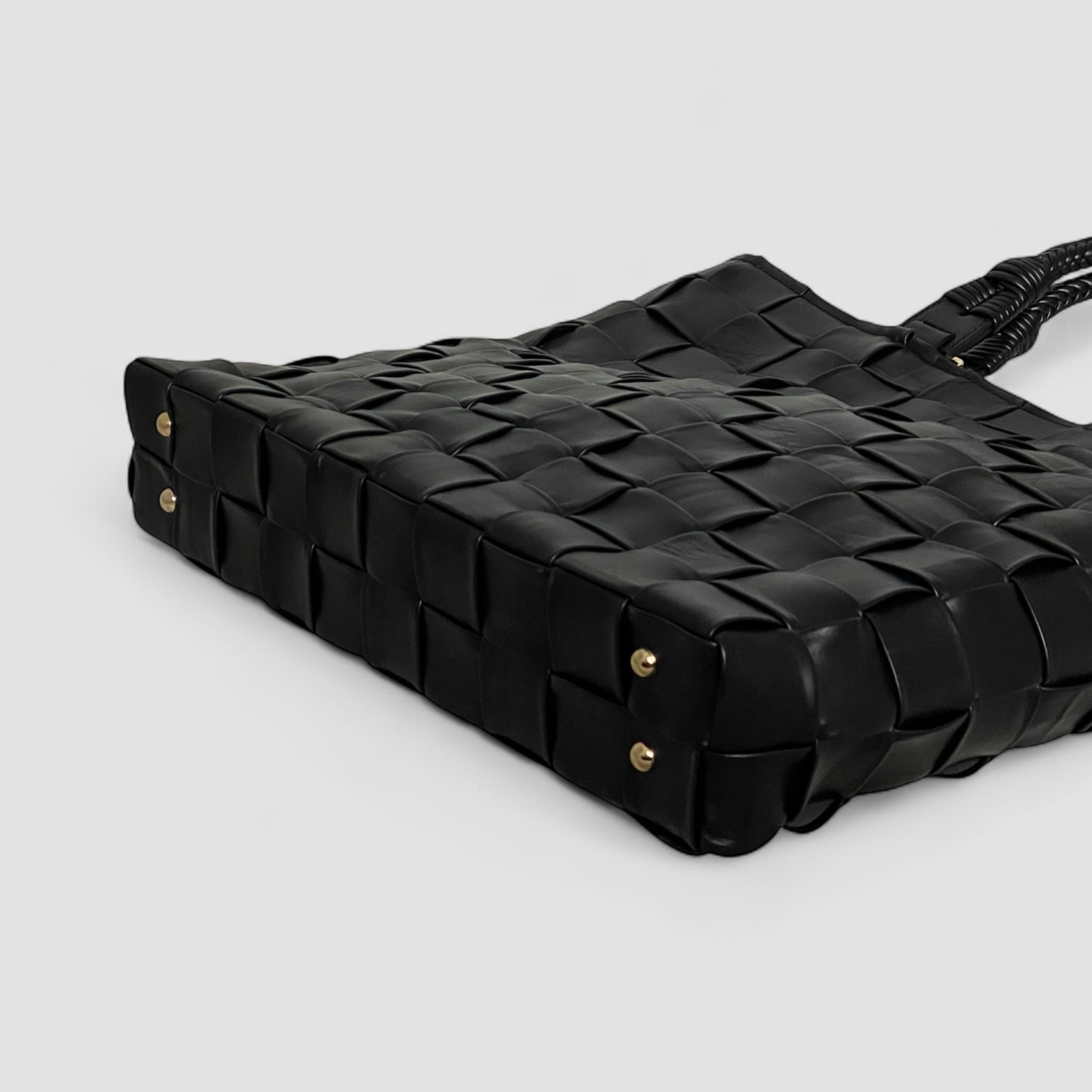 Under Ribichini Square skinnvesken i sort finnes elegante gullknotter. Disse tilfører eleganse og beskytter mot slitasje.