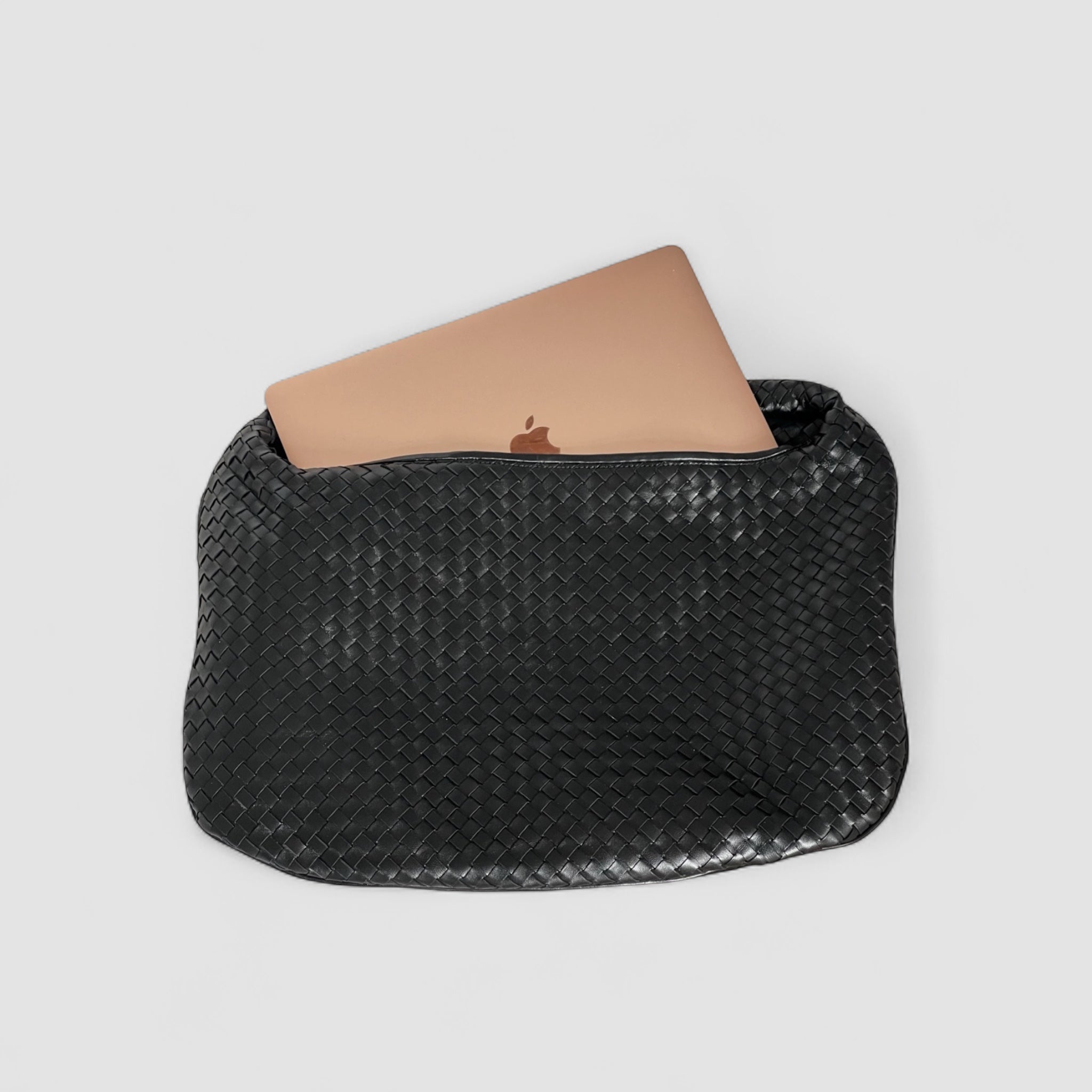 Ribichini Isola skinnveske i svart med flettet design, med plass til en bærbar datamaskin som stikker opp fra vesken.