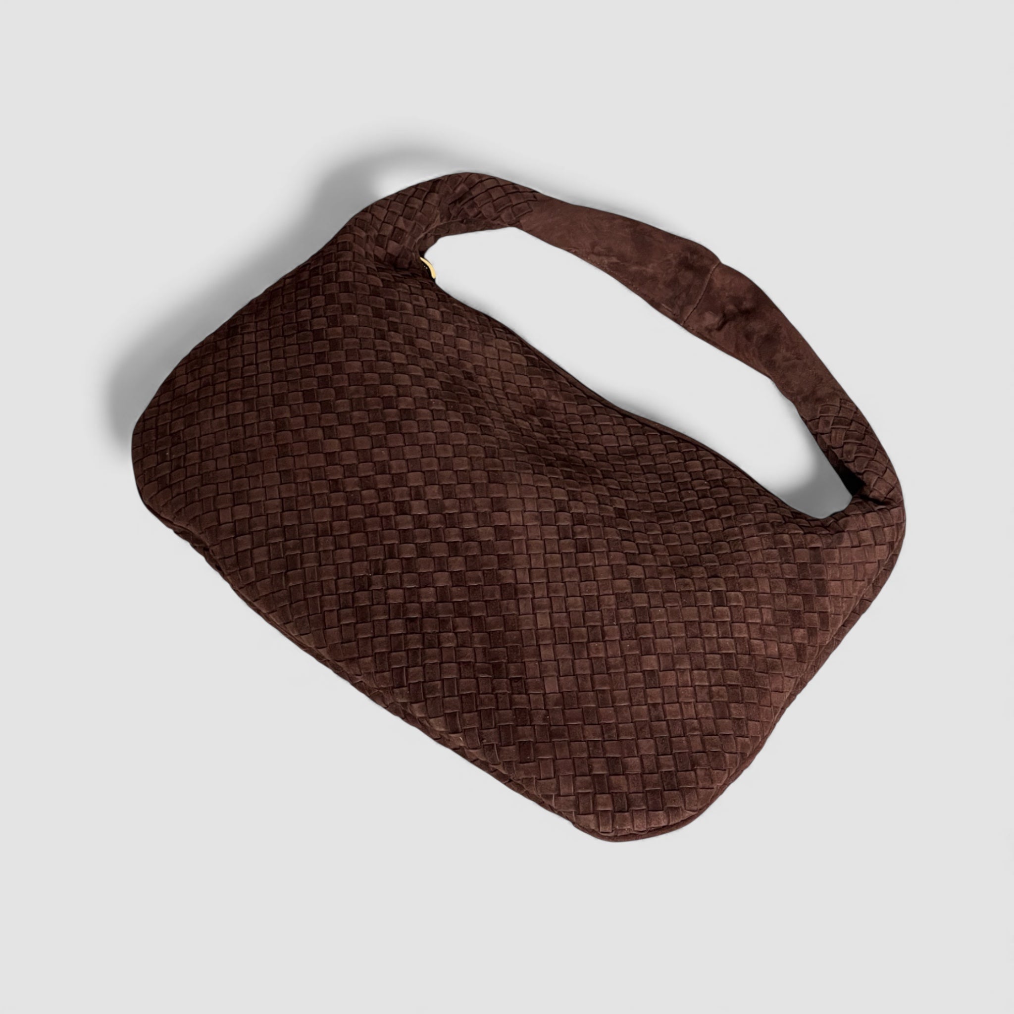 Bird's-eye view av Ribichini Isola royal semsket skinnveske i fargen chocolate, fremviser det flettede designet og den kurvede formen.