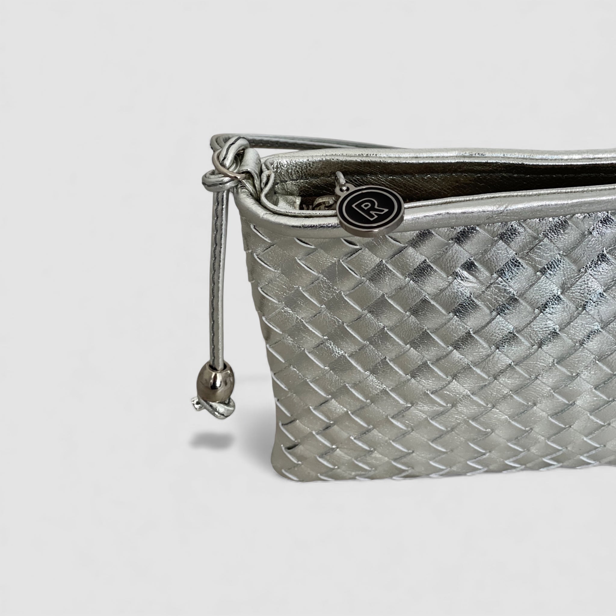 Ribichini Camper Clean Clutch i sølv: Flettet lammeskinn, sofistikert glans, ikonisk R-detaj i sølv. Elegant og stilfull.