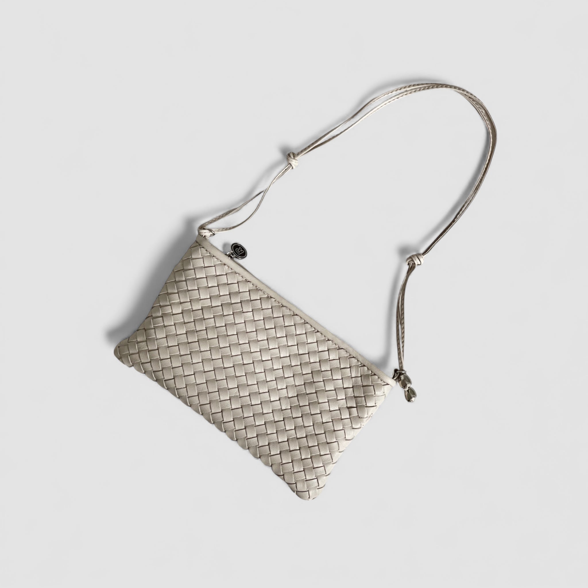 Ribichini Camper Clean Clutch i ice som ligger flatt. Flettemønsteret på lammeskinnet er tydelig.