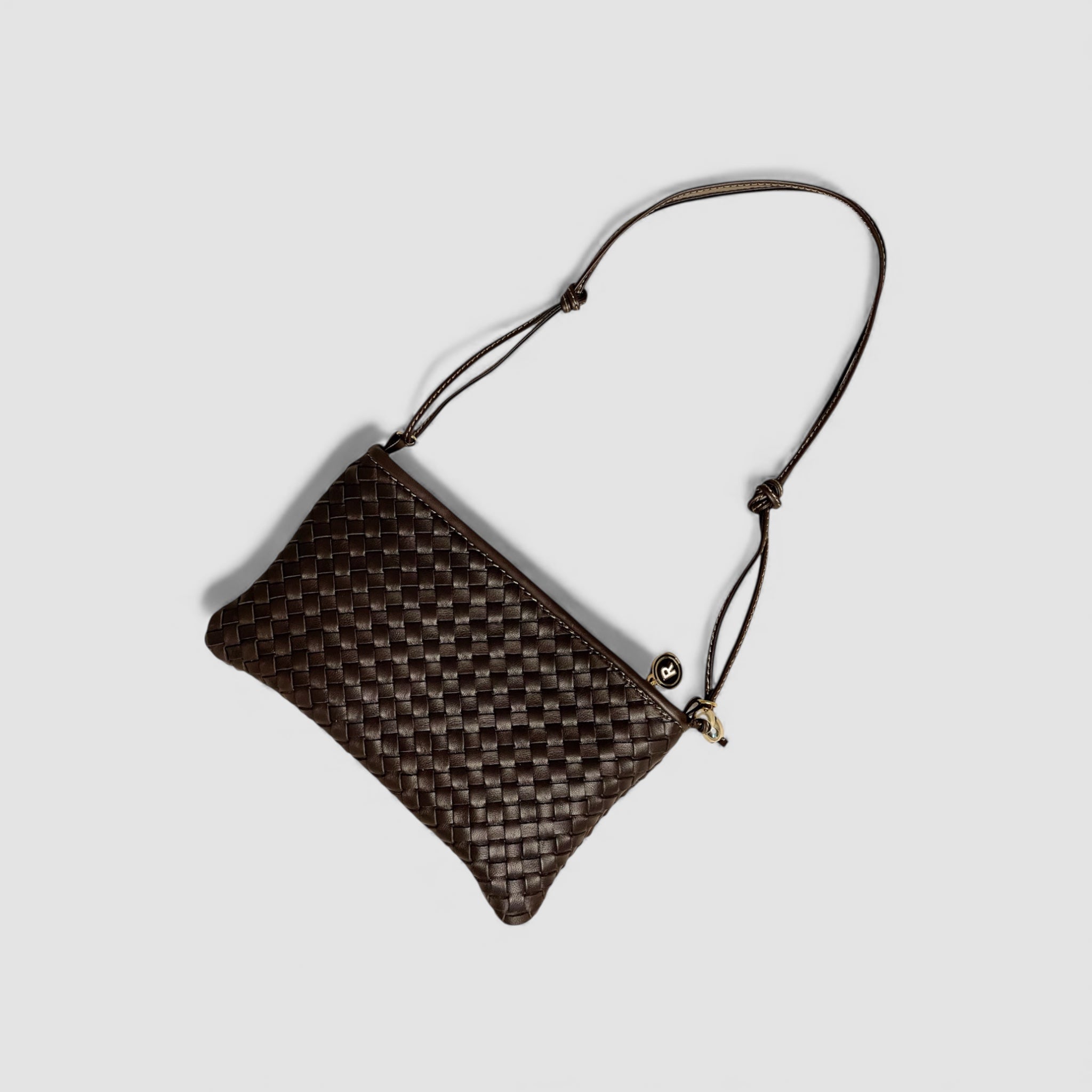 Ribichini Camper Clean Clutch i sjokoladefarge, flettet lammeskinn, og tydelige gulldetaljer, gir et luksuriøst utseende.