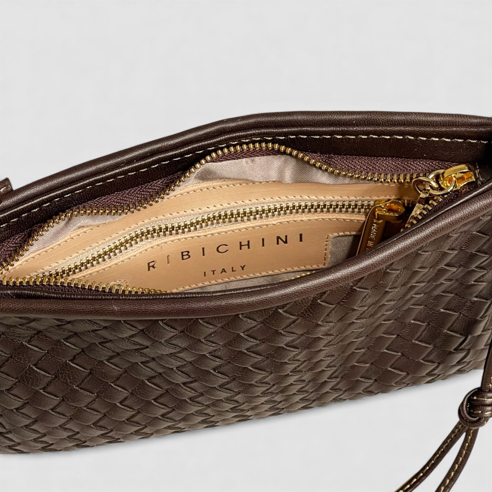 Ribichini Camper Clean clutch med beige fôr som kontrasterer det mørke lammeskinnet, den en glidelåslomme for trygg oppbevaring.