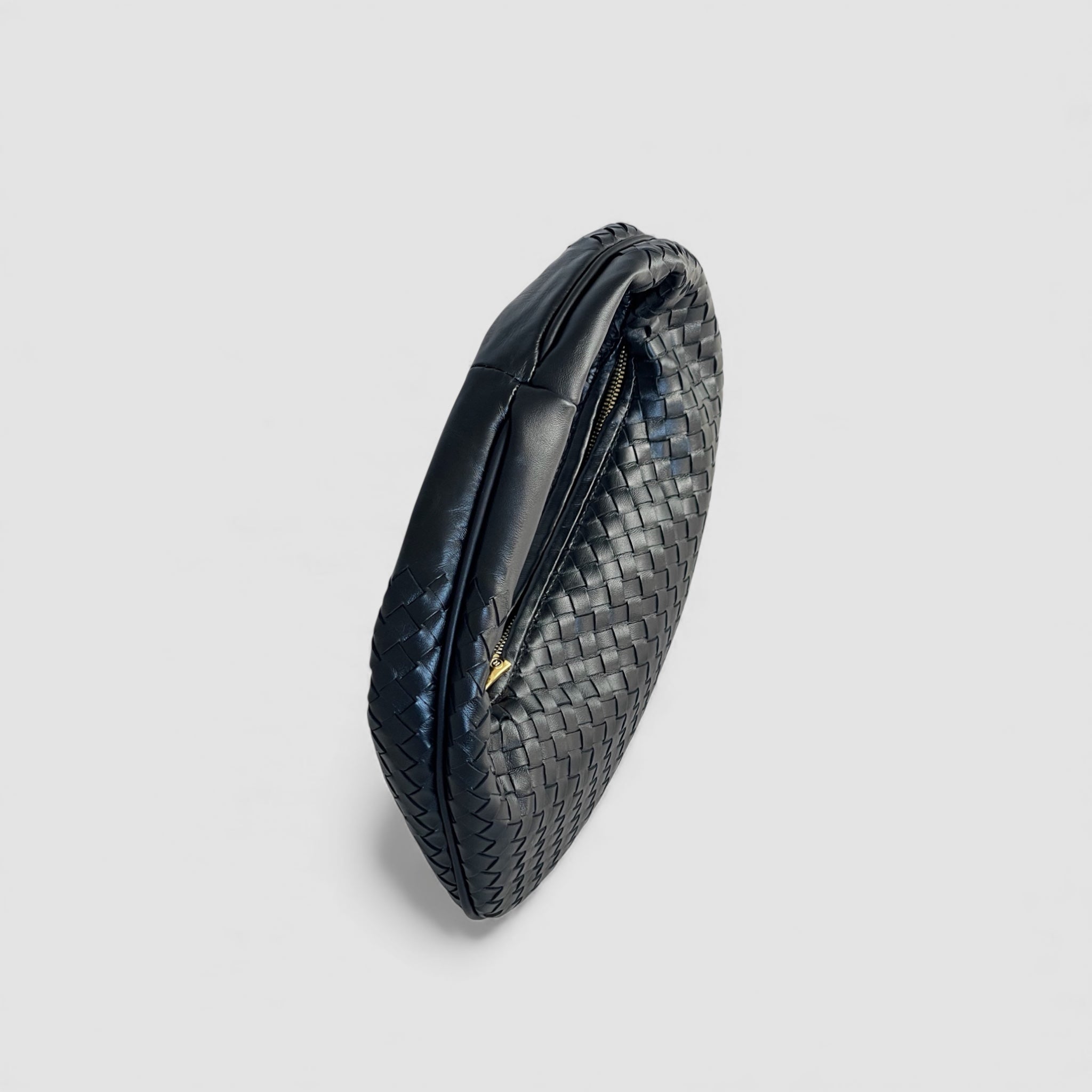 Ribichini Isola Bella i sort flettet skinn, sett fra siden med elegant, kompakt design og glidelås i gull.