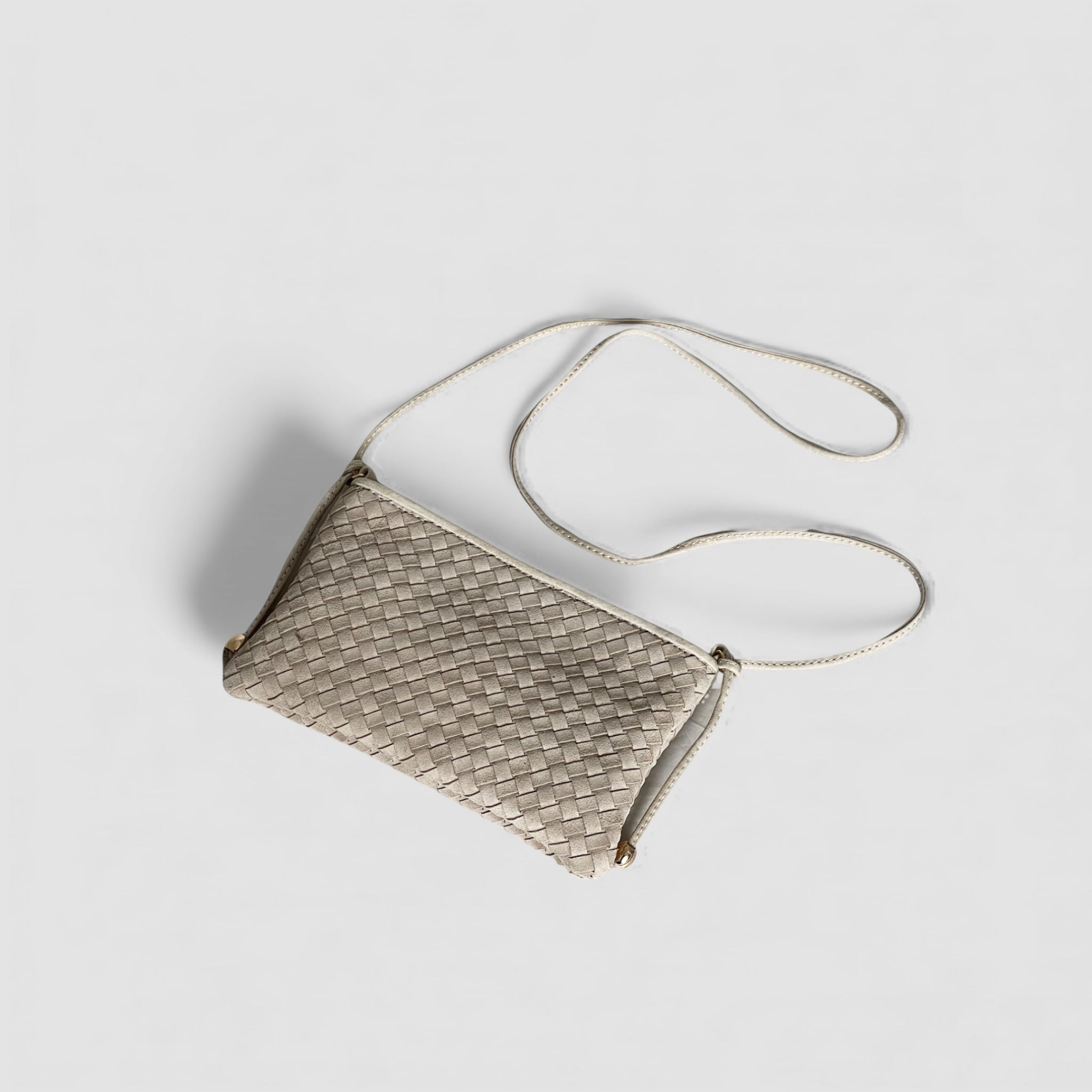 Ribichini Camper clutch i fargen sand i semsket lammeskinn med flettet design og lang skulderrem, vist ovenfra.