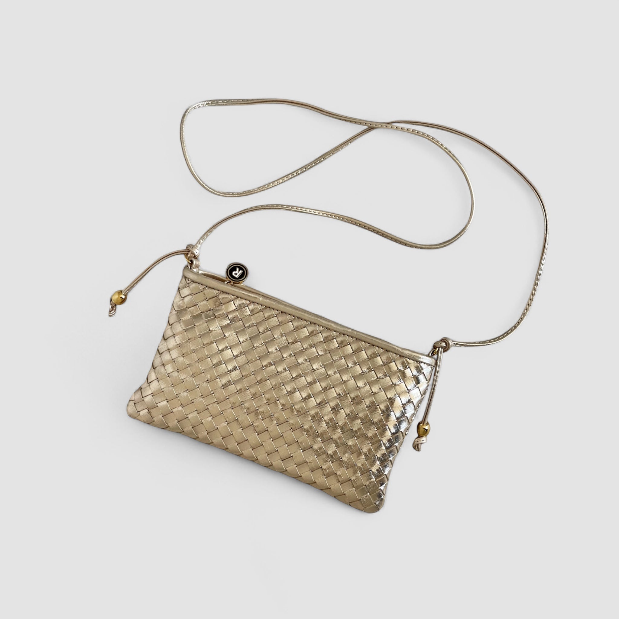 Ribichini Camper Clean Clutch i gull liggende: Flettet lammeskinn og elegante gulldetaljer fremhever veskens unike design.