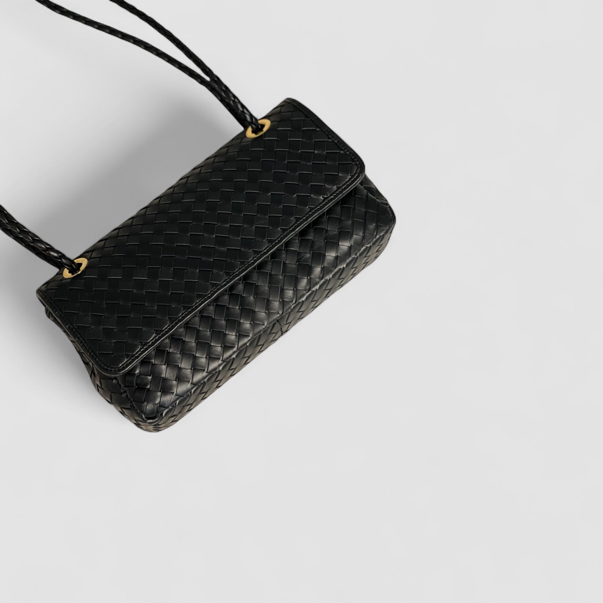 Bildet gir et fugleperspektiv av Ribichini Envelope-clutchen med sort flettet lammeskinn og fine gull-detaljer.