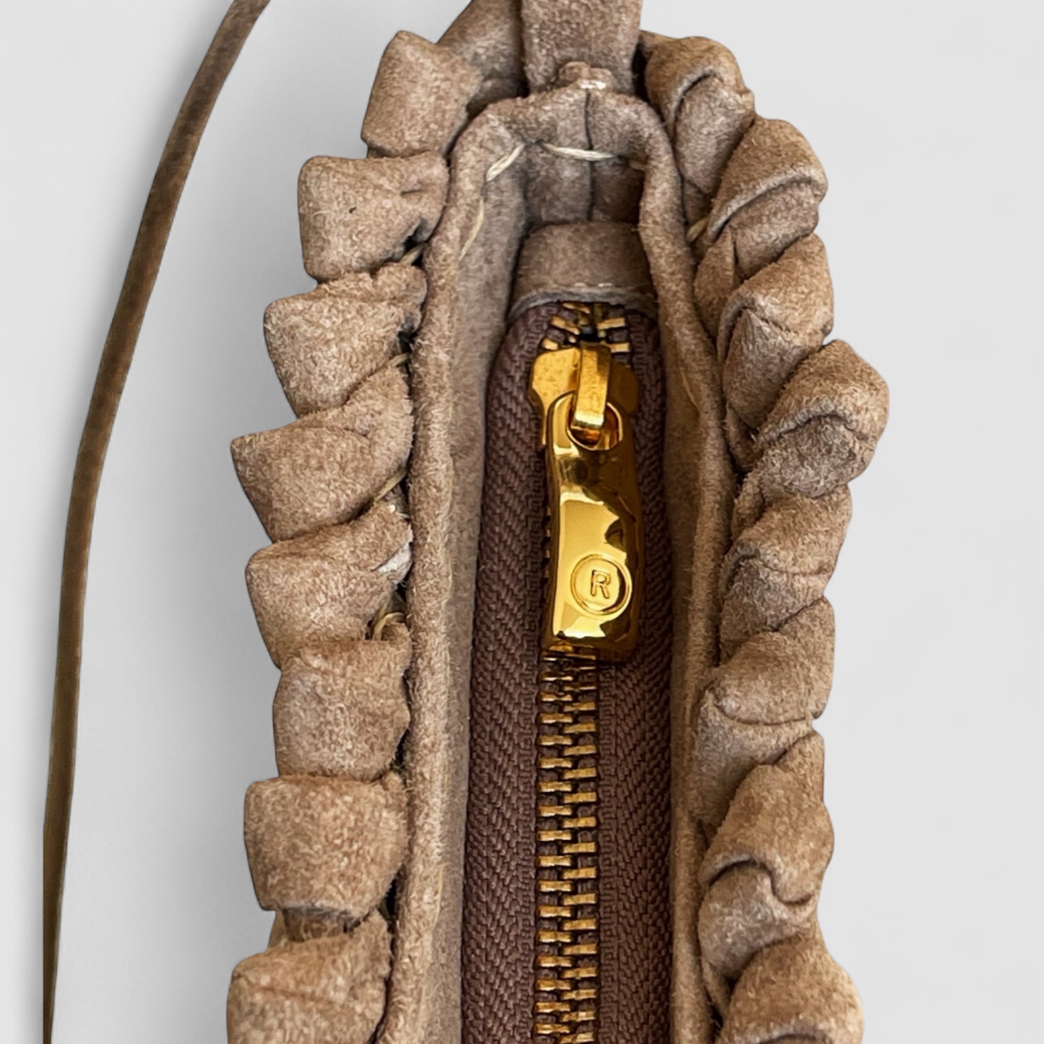 Nærbilde av gullglidelås med "R"-detalj på Ribichini Woodstock Royal clutch i terra semsket skinn, med flettet design.