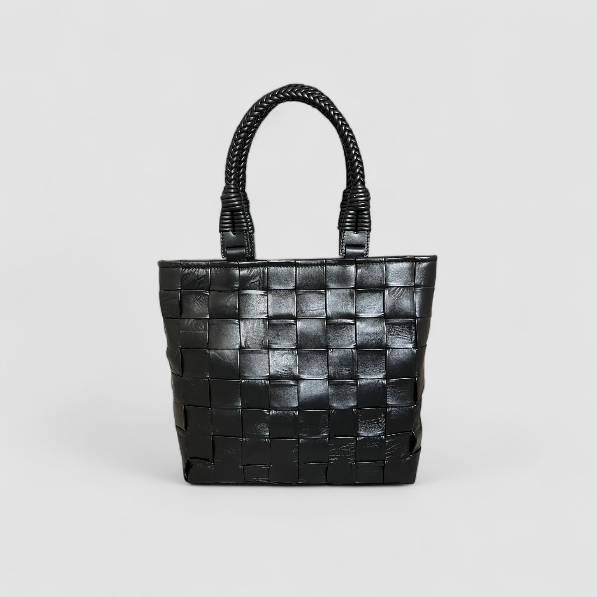 Ribichini Square Babe i sort, laget av håndflettet lammeskinn. Vesken har en unik design med store, generøse ruter og flettede hanker.