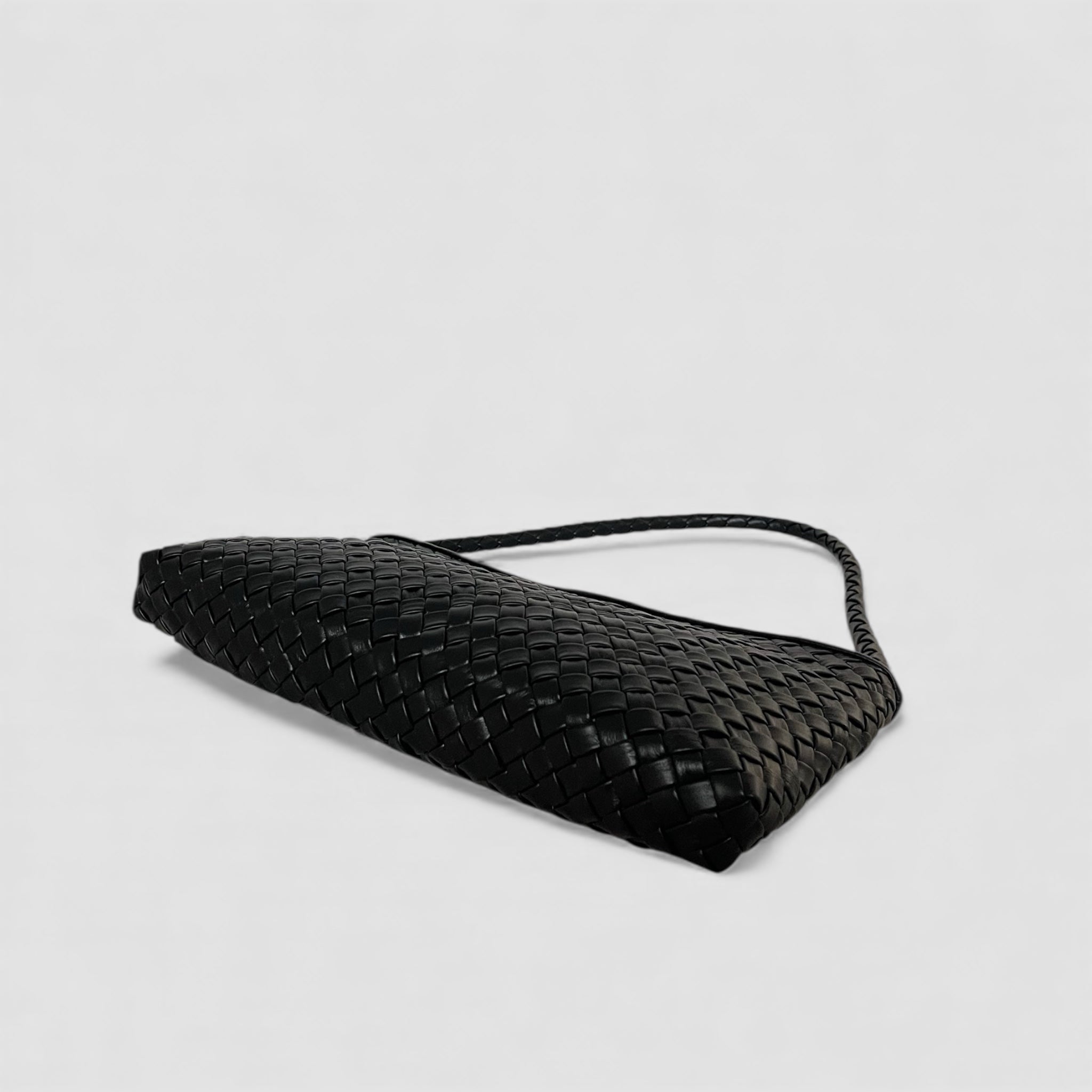 Sort Ribichini Classica i håndflettet skinn, vist nedenfra i liggende posisjon med flettet stropp mot lys bakgrunn.
