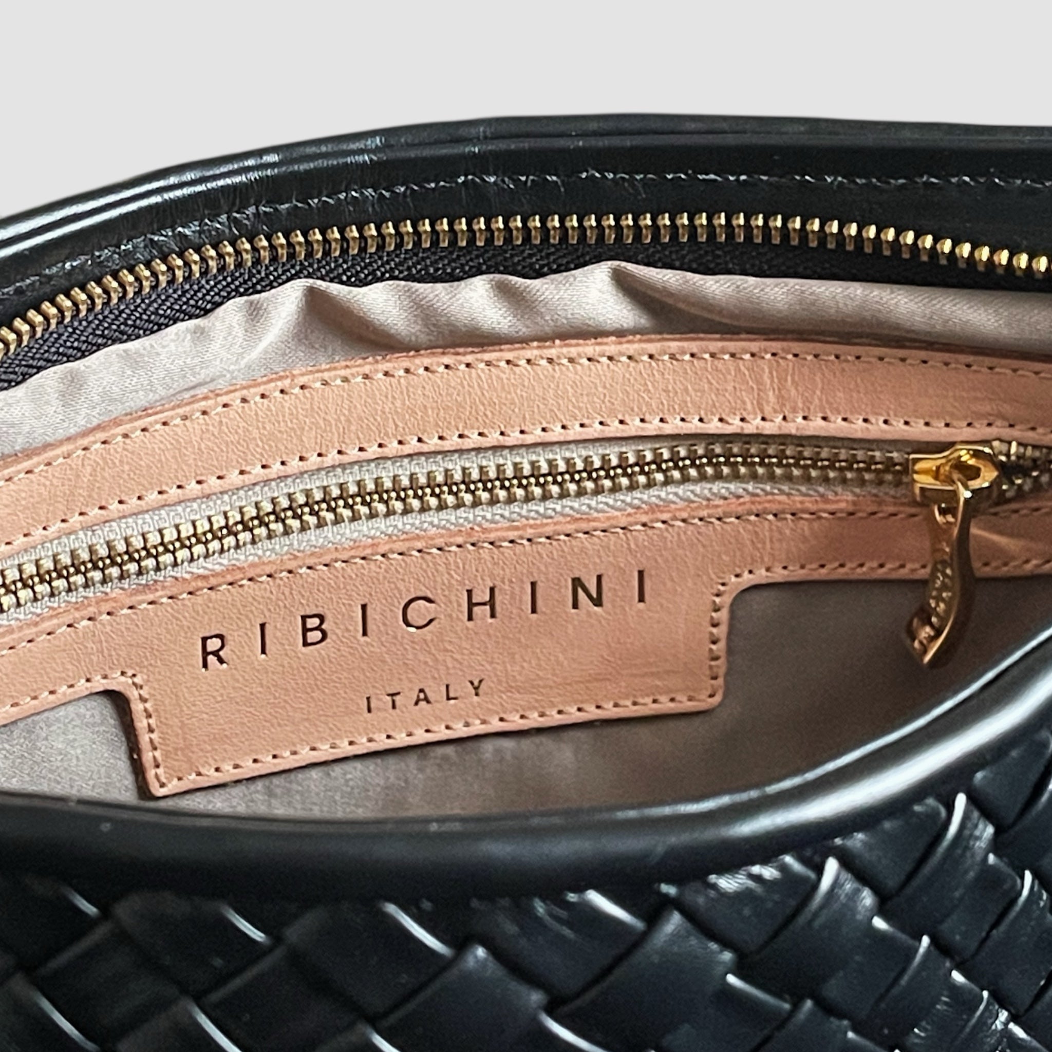 Detalj av innsiden på Ribichini Classica med beige skinnpanel, gullglidelås og RIBICHINI Italy logo.