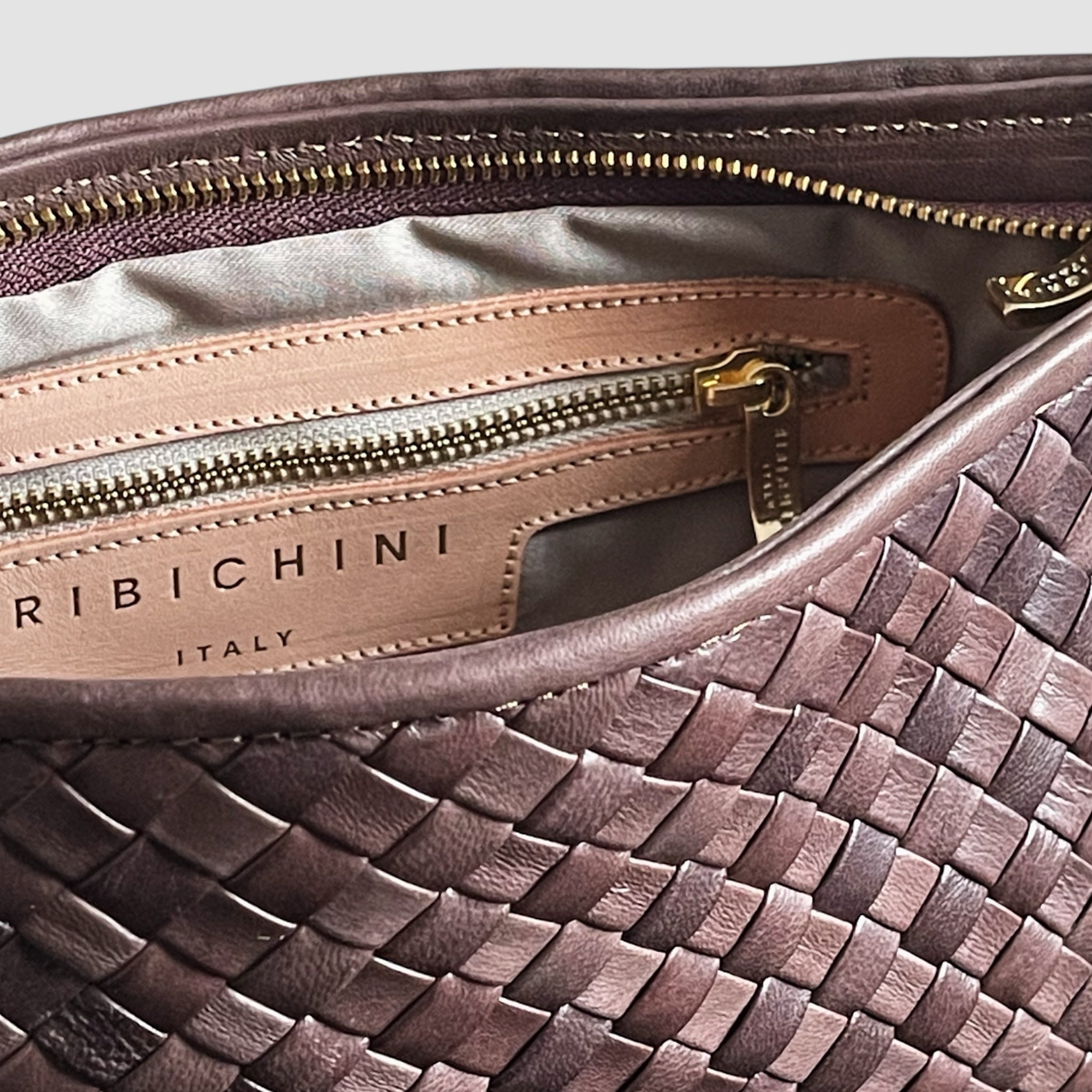 Detalj av innsiden på brun Ribichini Classica med beige skinnpanel, gullglidelås og RIBICHINI Italy logo.