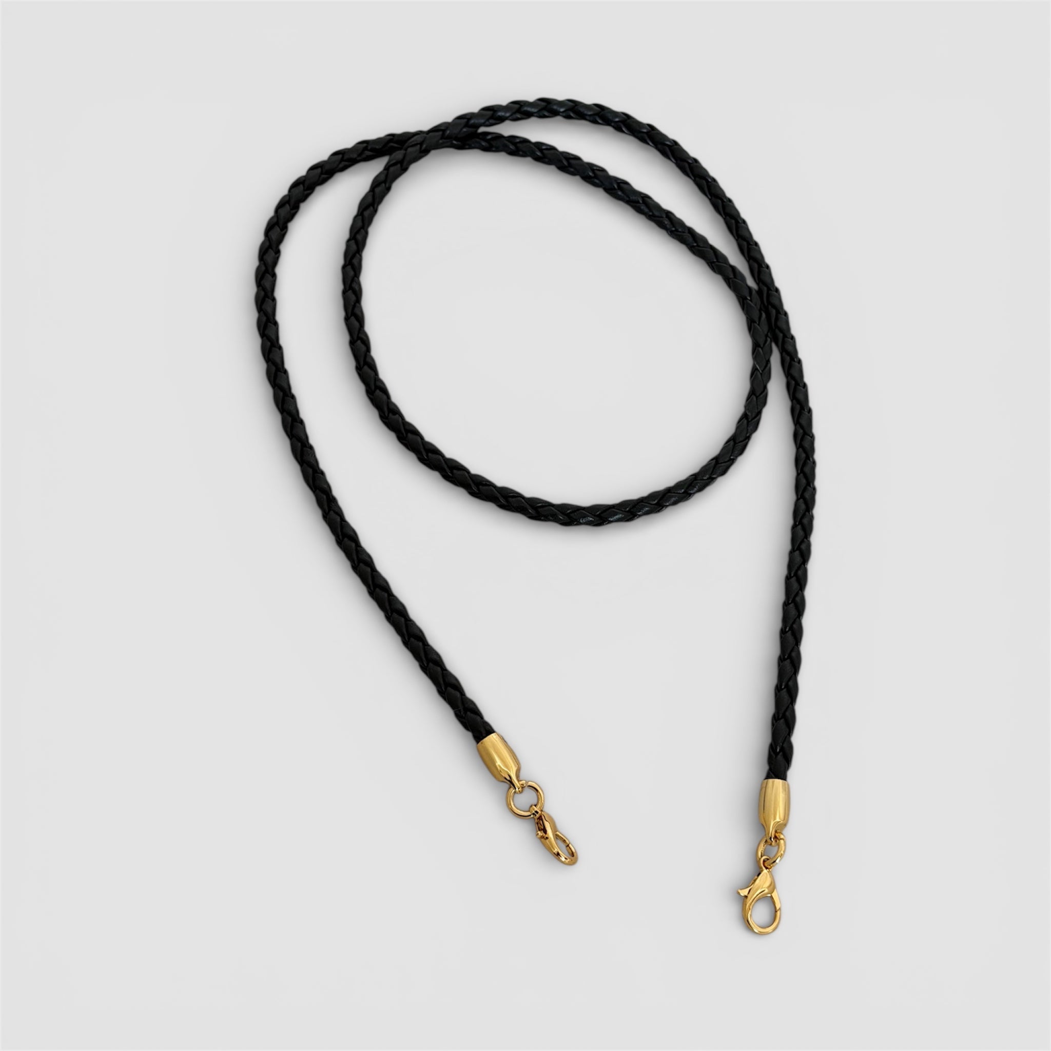 Avtagbar flettet skulderstropp i sort skinn med gullfargede karabinkroker, håndlaget i Italia.