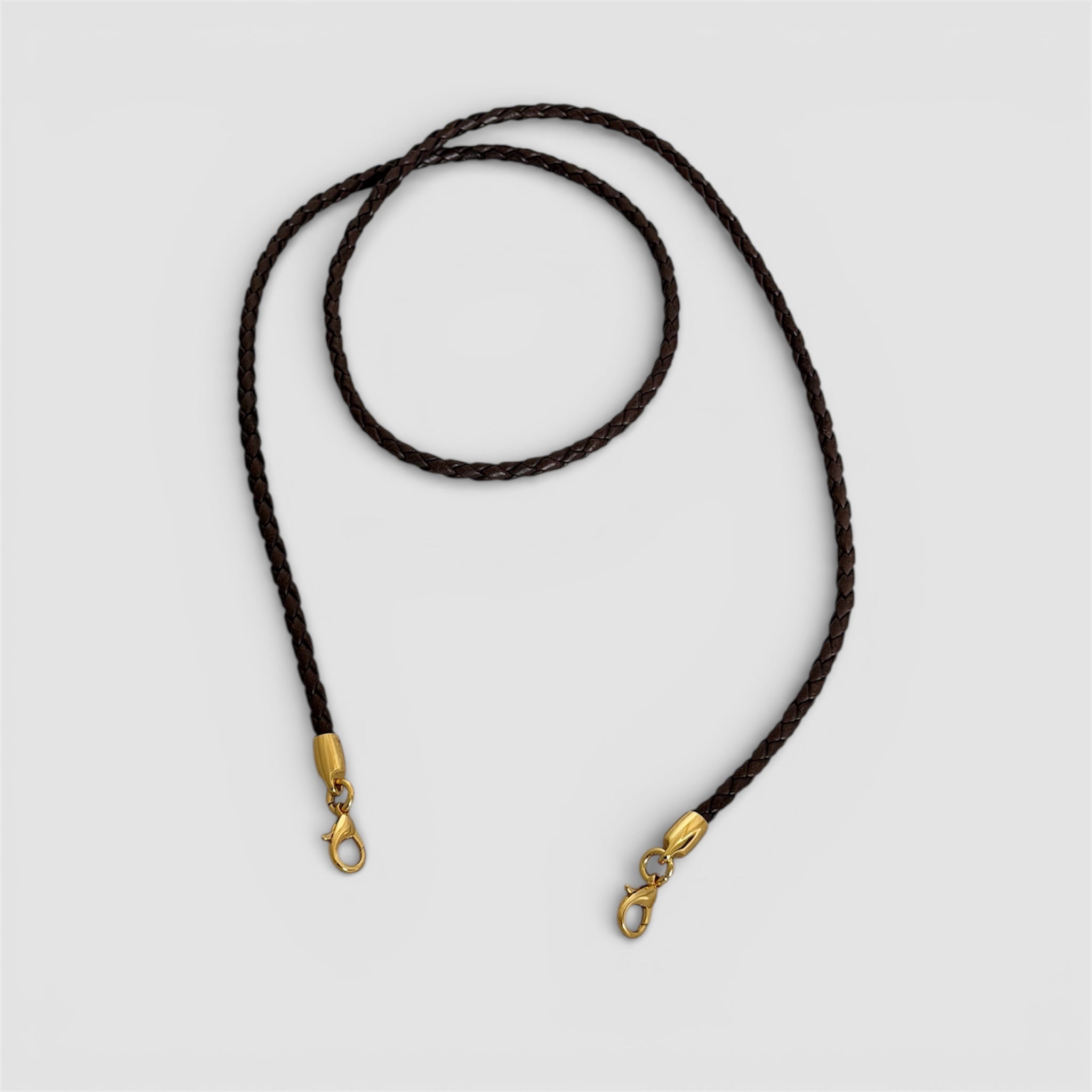 Avtagbar flettet skulderstropp i brunt skinn med gullfargede karabinkroker, håndlaget i Italia.