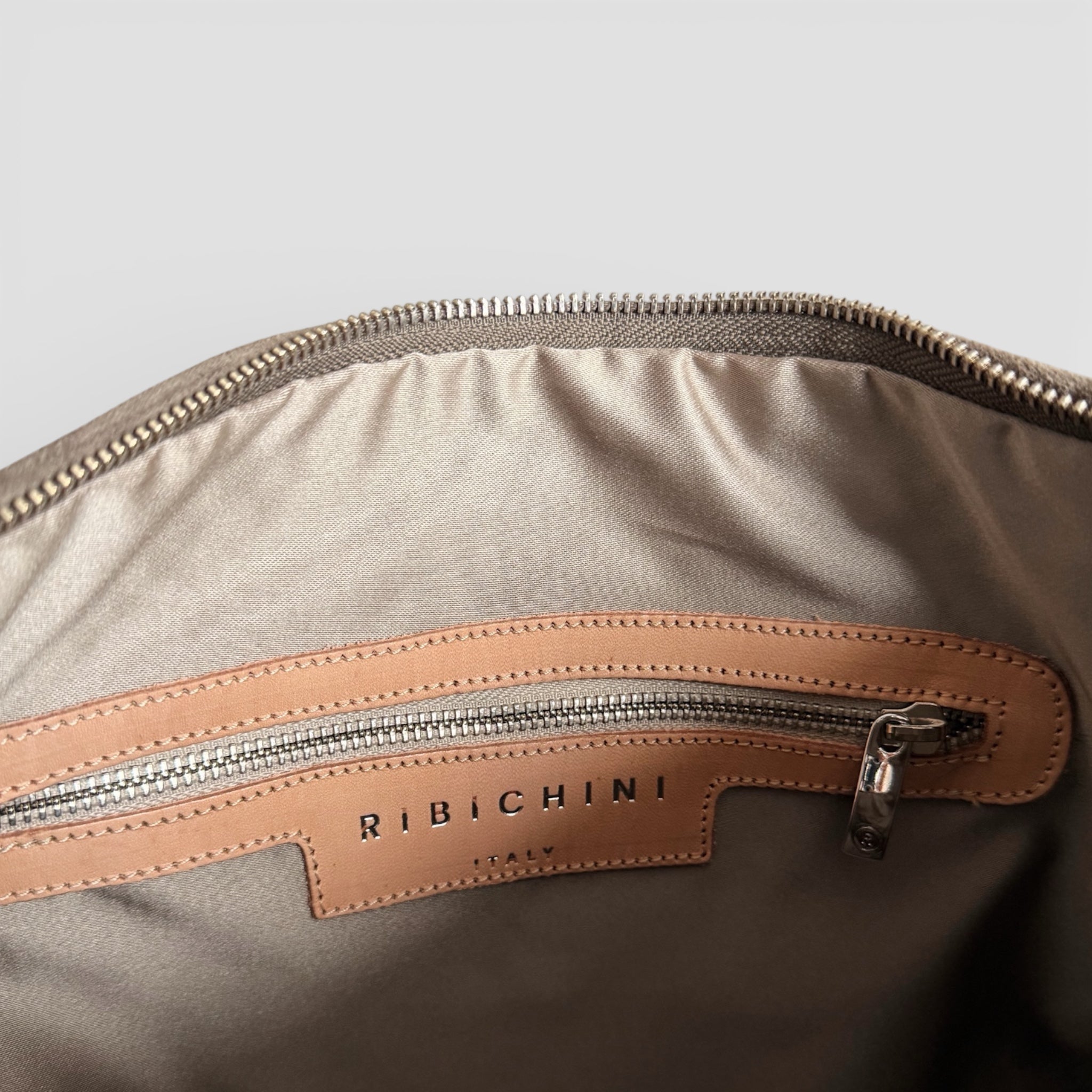Innvendig detaljbilde av Ribichini Isola Royal Smoke med glidelåslomme, tekstilfôr og skinnetikett merket Ribichini Italy.