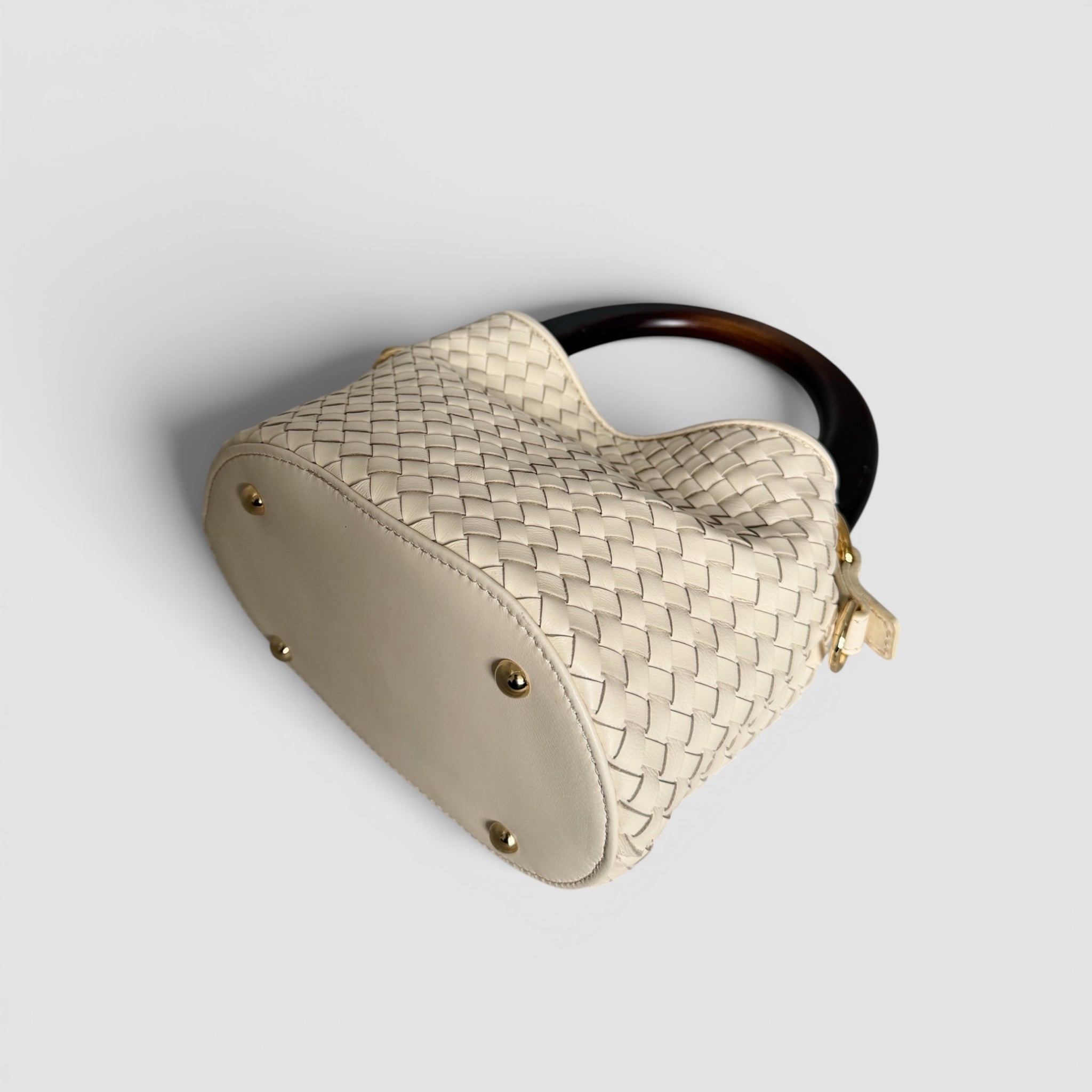 Ribichini Albero Cream håndflettet italiensk skinnveske i lammeskinn sett nedenfra med rund bunn og metallføtter