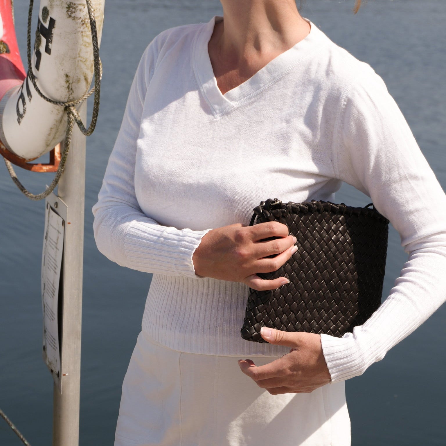 Ribichini Woodstock Clutch chocolate håndflettet clutch i italiensk lammeskinn ved sjøen.