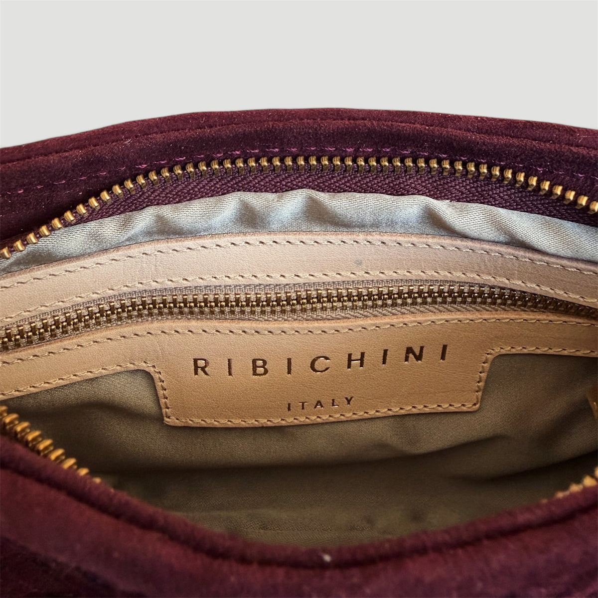 Ribichini Camper Clutch Suede Bordeaux – detaljbilde av innsiden med glidelåslomme, skinnetikett og Ribichini Italy-logo.