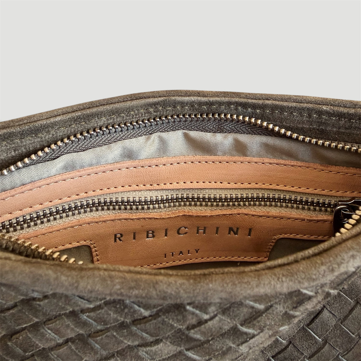 Ribichini Camper Clutch Suede Olive – detaljbilde av innsiden med glidelåslomme, skinnetikett og Ribichini Italy-logo.