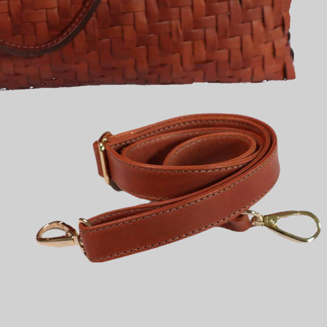 På bildet kan man se den avtagbare skulderstroppen med elegante gulldetaljer som følger med en Ribichini Safari-veske i cognacfarge.