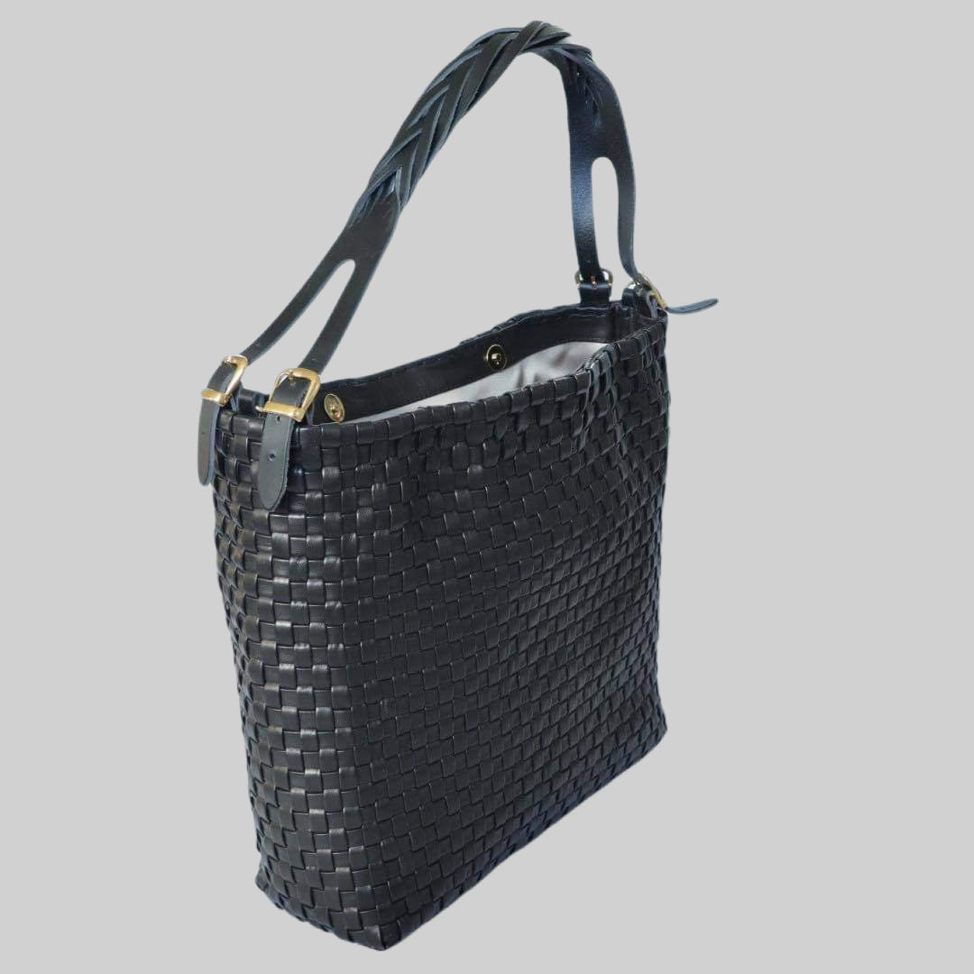 Ribichini Camper Clean skinnveske i sort lammeskinn, med matchende flettet hank og elegante gulldetaljer, gir et snev av luksus. Skråvinklet perspektiv fremhever formen.