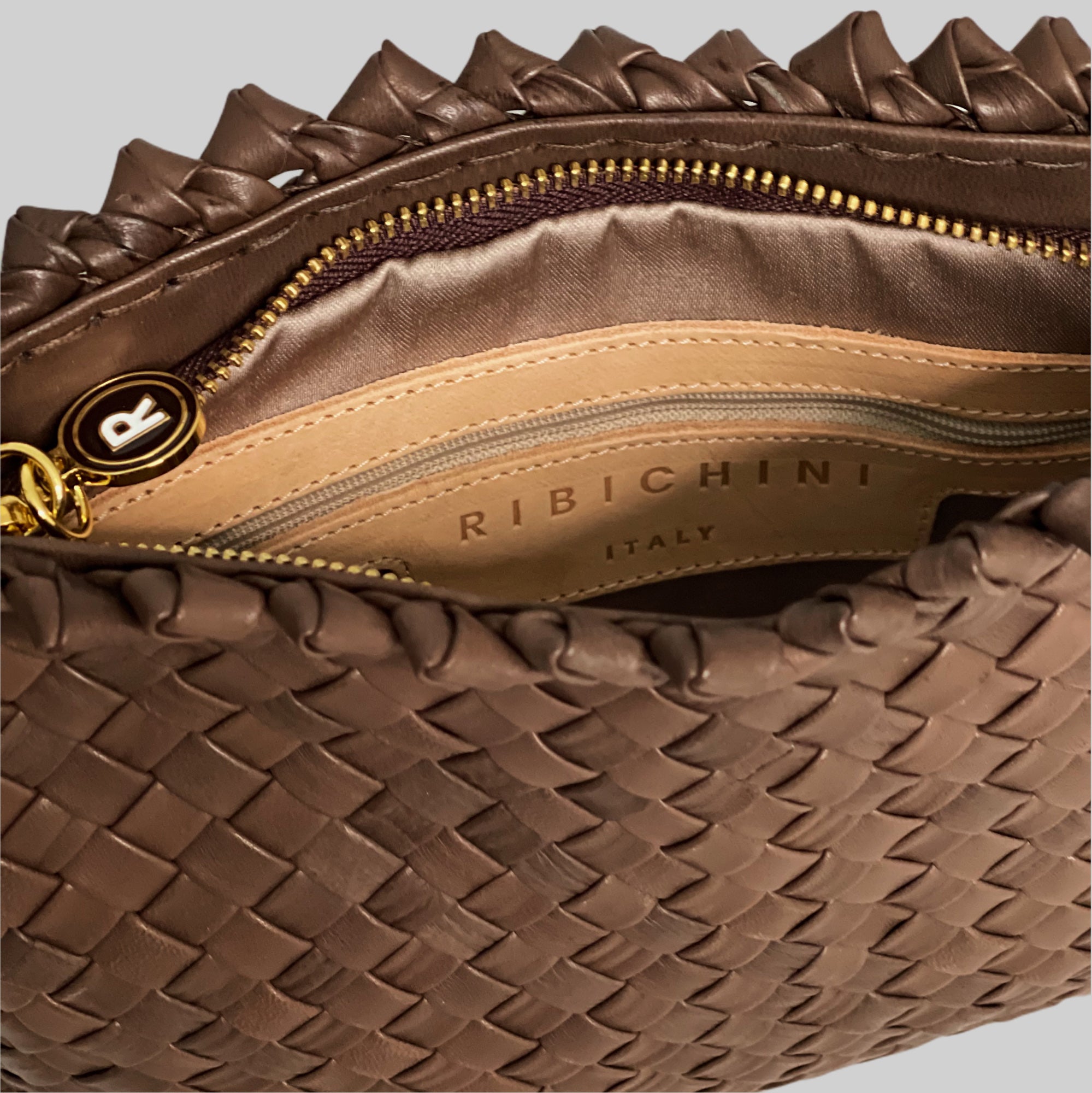 Innsiden av den brune Ribichini Woodstock-clutchen er organisert med glidelåslomme og åpne lommer.