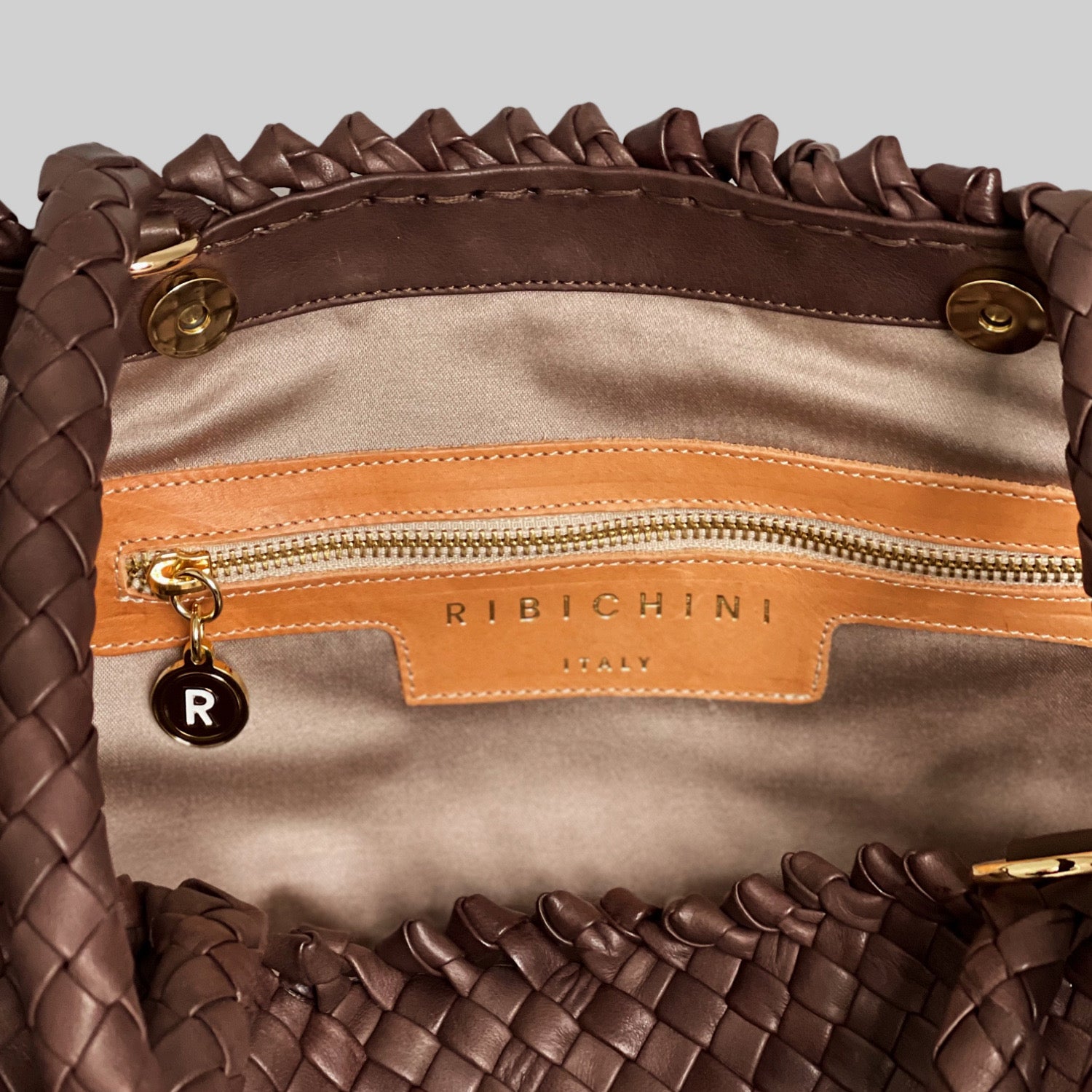 Ribichini Woodstock Weekend-brun veskeinteriøret viser italiensk estetikk med etikett, glidelås og kontrastfylt innerfôr.