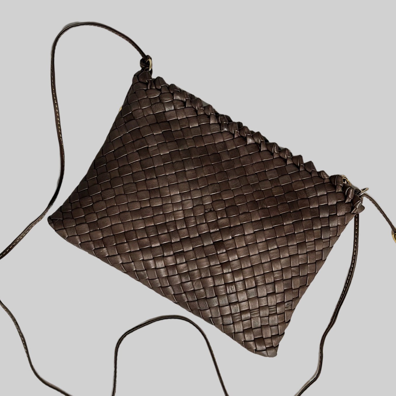 Ribichini Woodstock clutch i brunt skinn, med skulderrem og gylne detaljer. Flettet mønster gir rik tekstur.