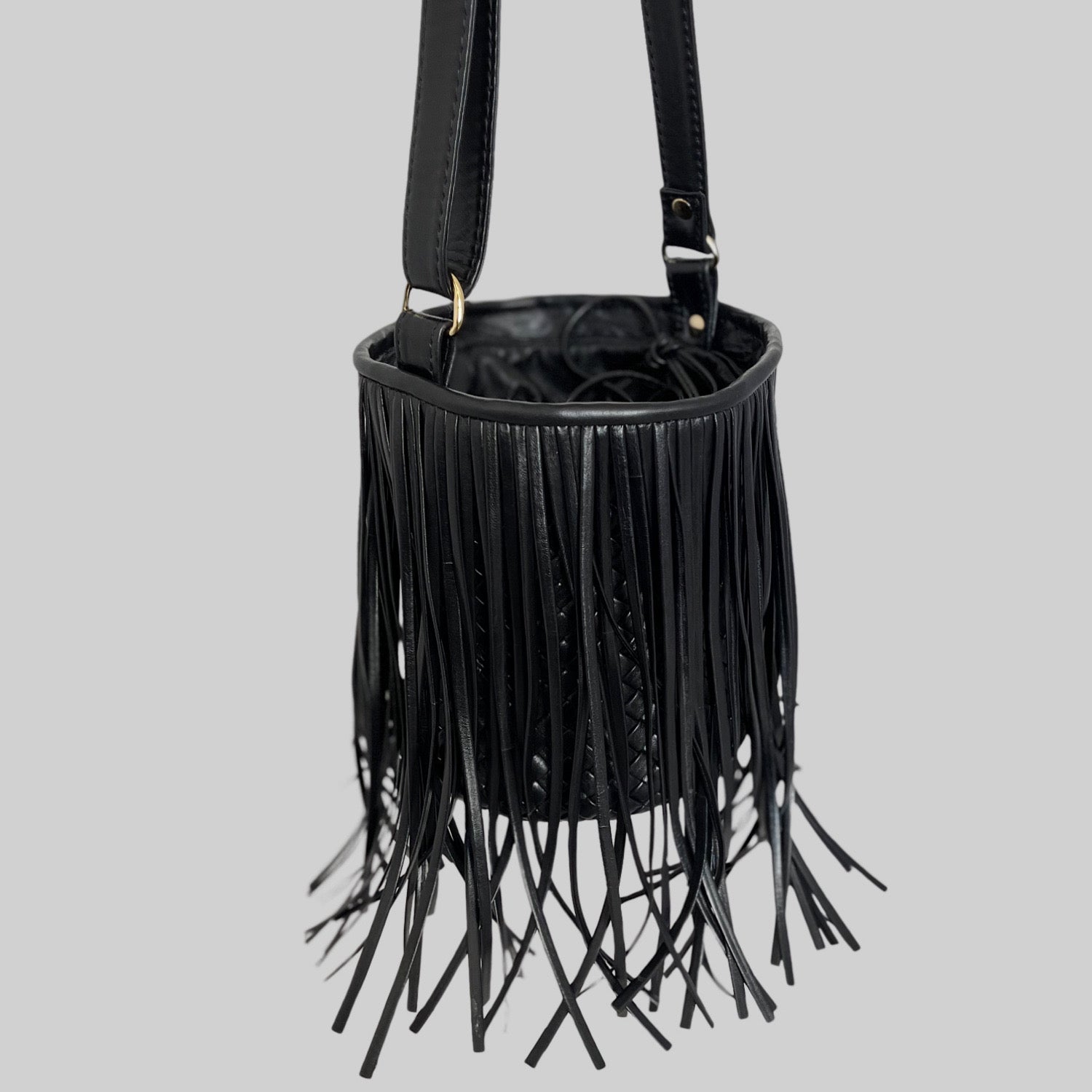 Ribichini Bucket i sort med sine flyvende frekke frynser, gulldetaljer og bucket-formen som bare ber om å få komme ut for å ta imot misunnelige blikk.