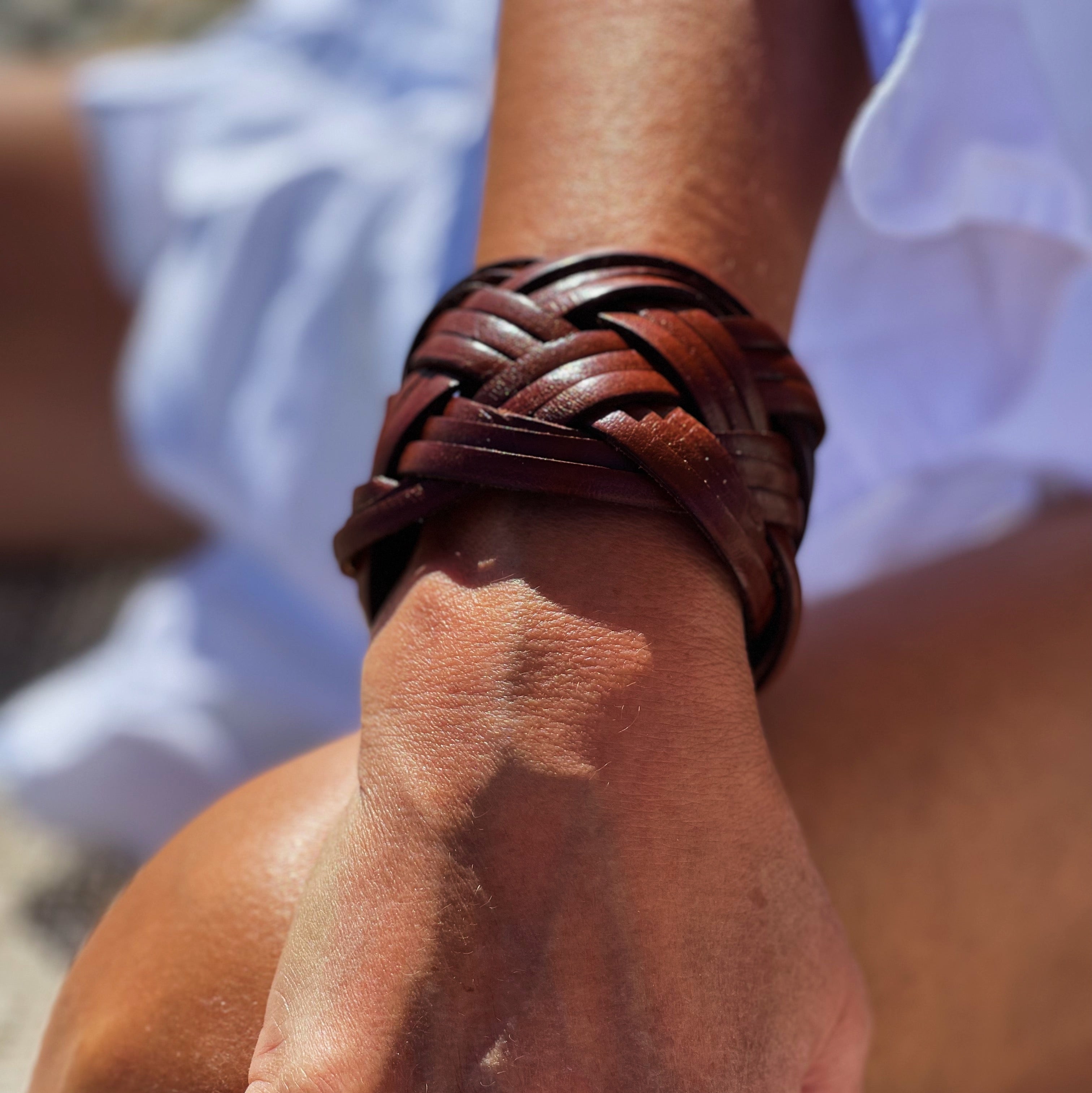 Solbrun hånd med et vakkert flettet armbånd i fargen oak fra Ribichini. 
