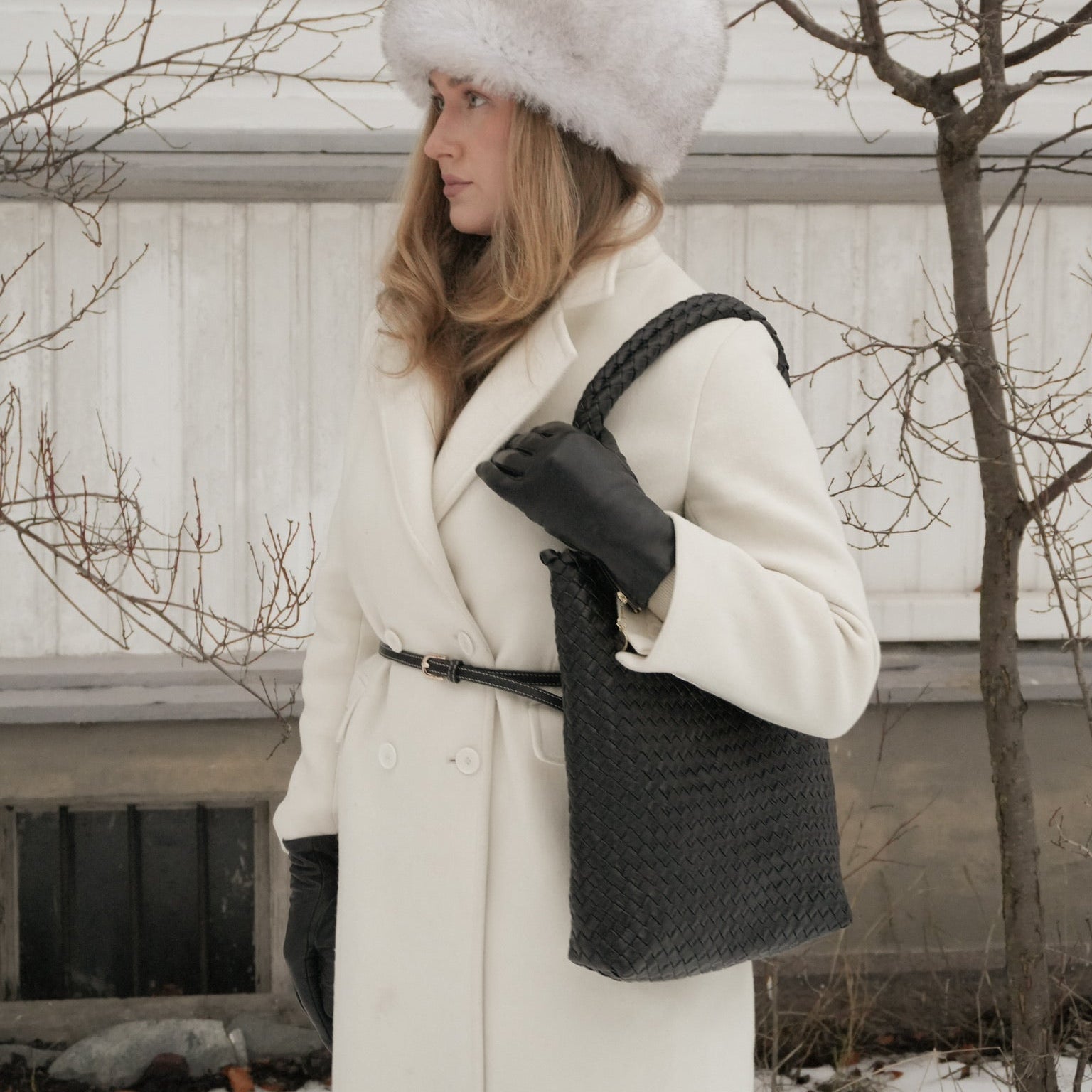 Woodstock Babe – håndflettet skulderveske i sort skinn, brukt over skulderen med flettet hank og tidløst design.