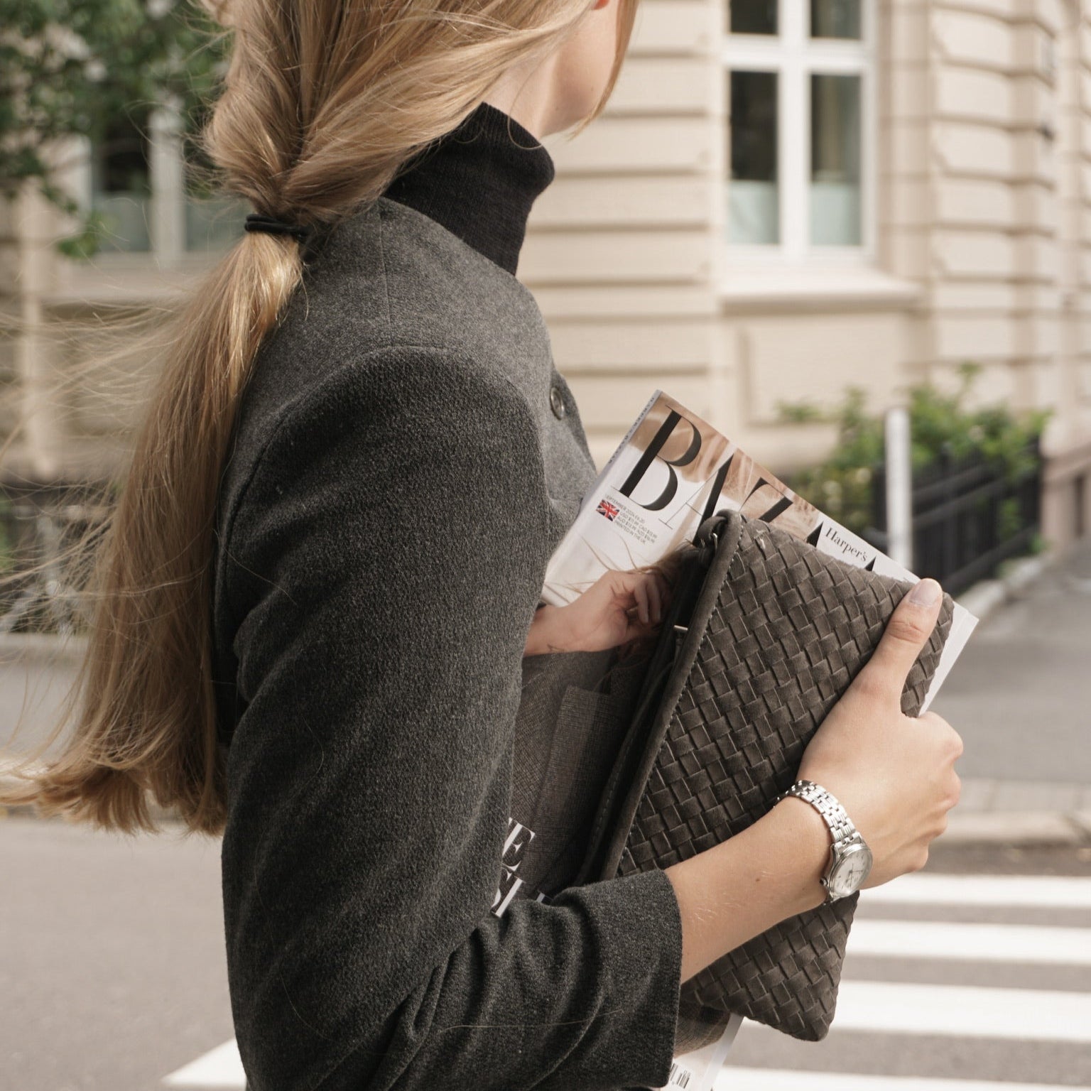 Kvinne med Ribichini Camper Clutch i semsket lammeskinn, farge Graphite, holdt sammen med Harper’s Bazaar magasin.