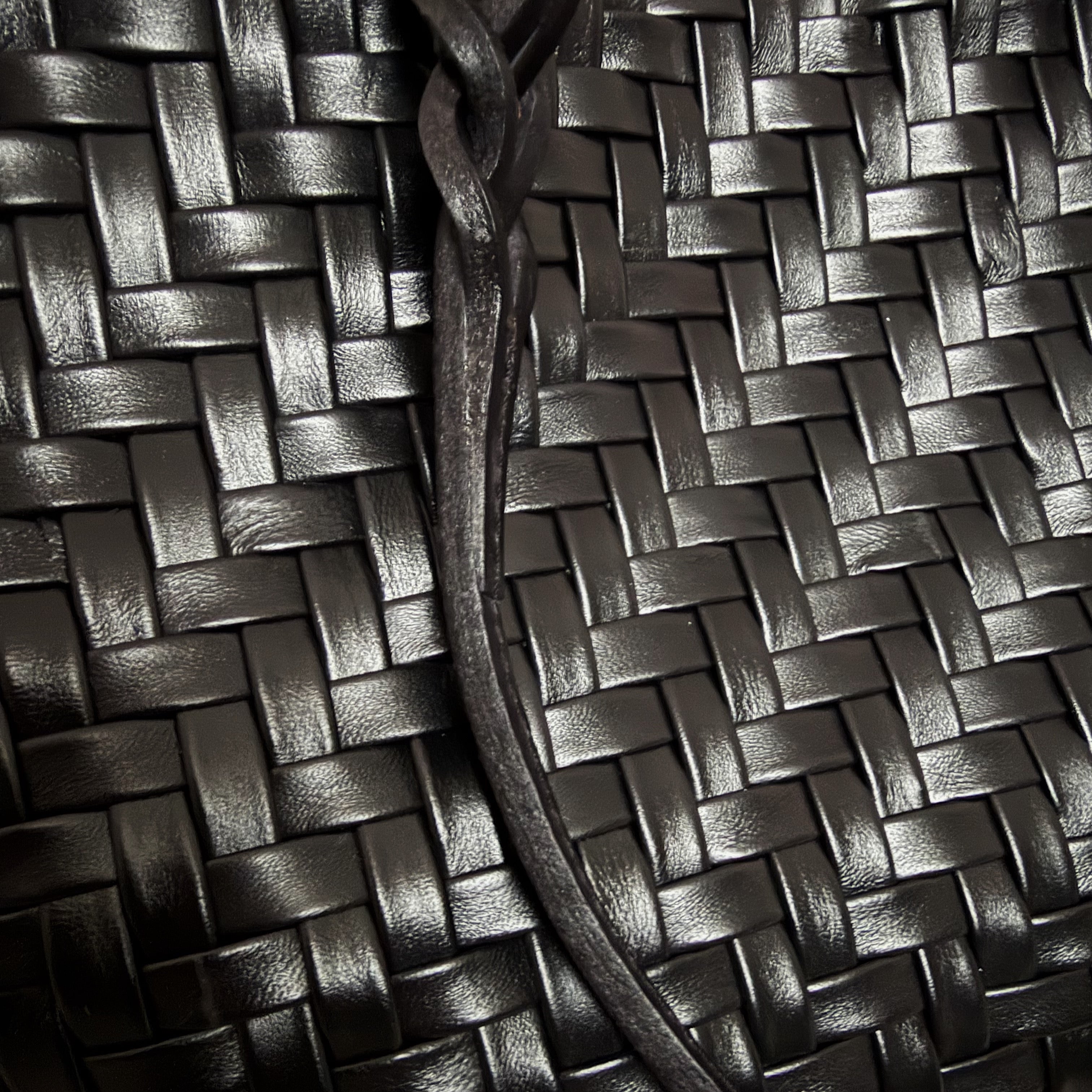 Safari i sort – detaljert nærbilde av håndflettet skinn og flettet stropp.