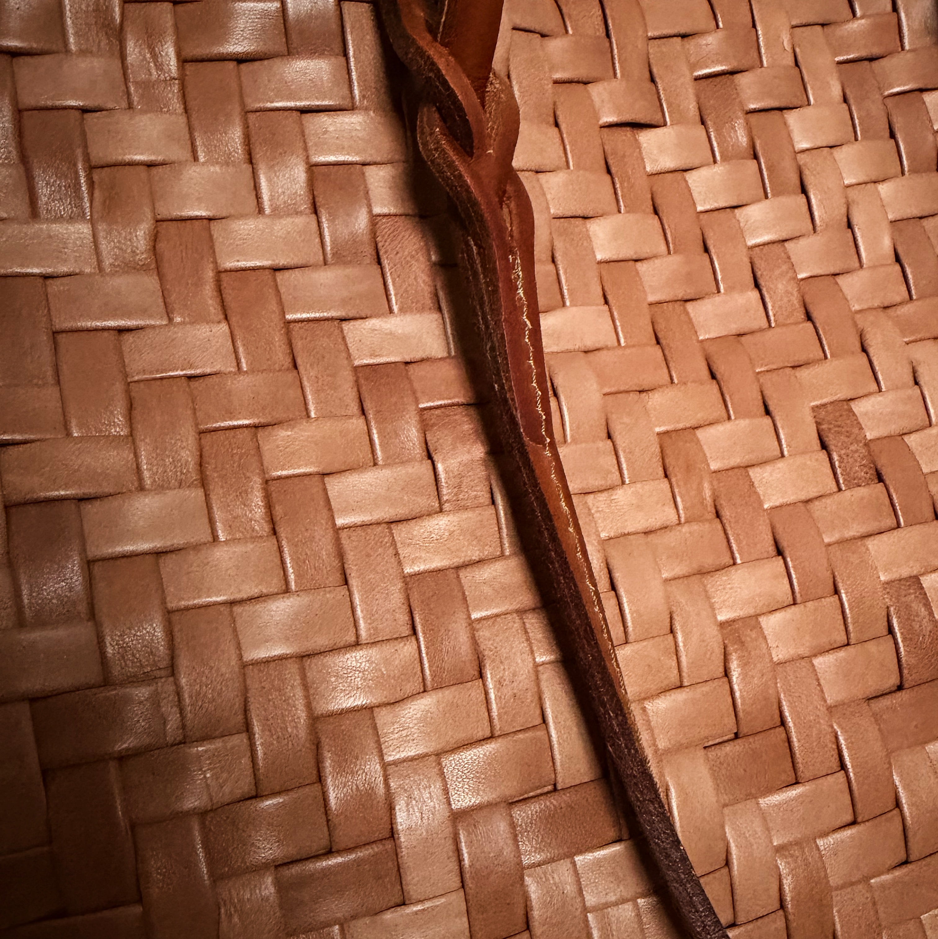 Safari i cognac – detaljert nærbilde av håndflettet skinn og flettet stropp.