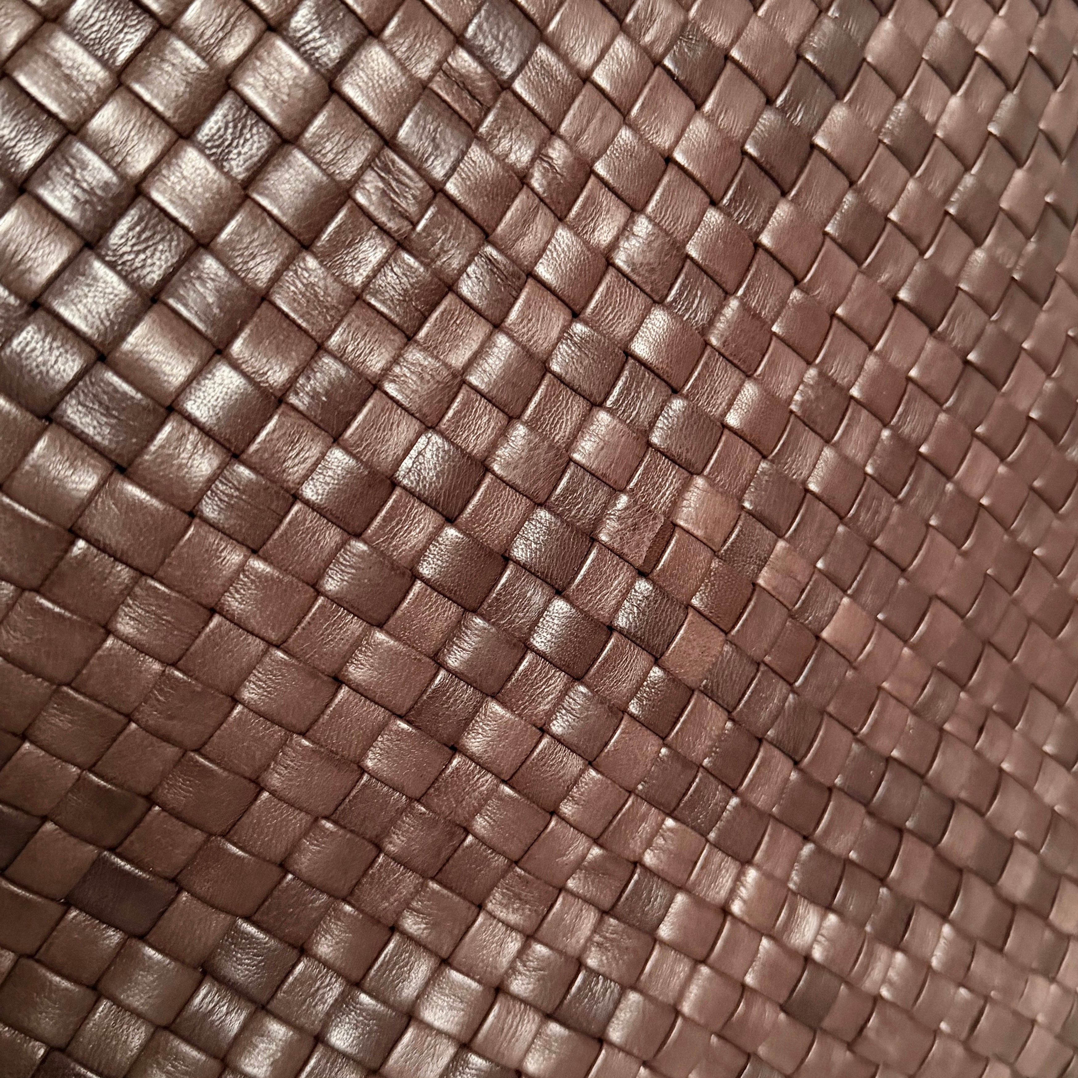 Detaljbilde av håndflettet skinn i brunt med tett flettestruktur.