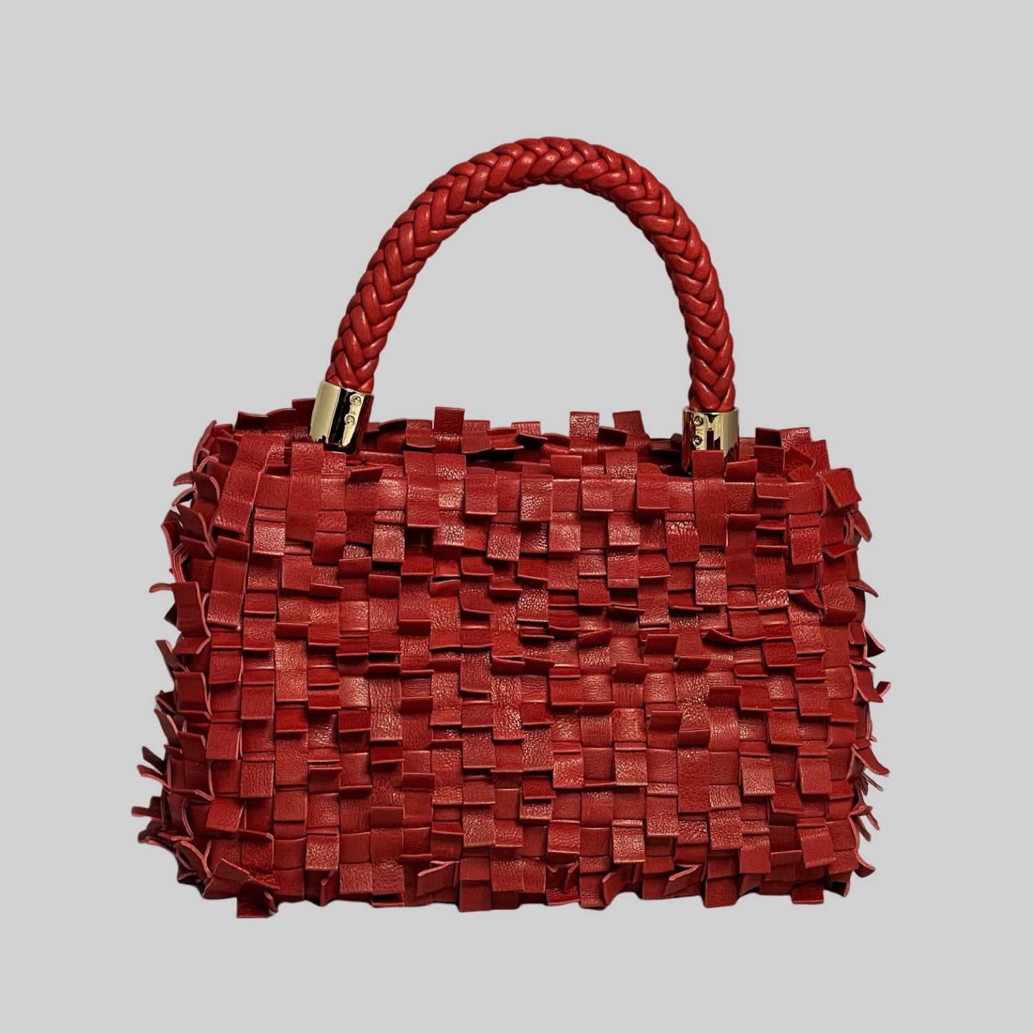 Ribimini-vesken i rødt skinner med sin unike tekstur og flettet design. Solid håndtak og gullfargede detaljer legger til eleganse, og den kompakte størrelsen gir praktisk bruk.