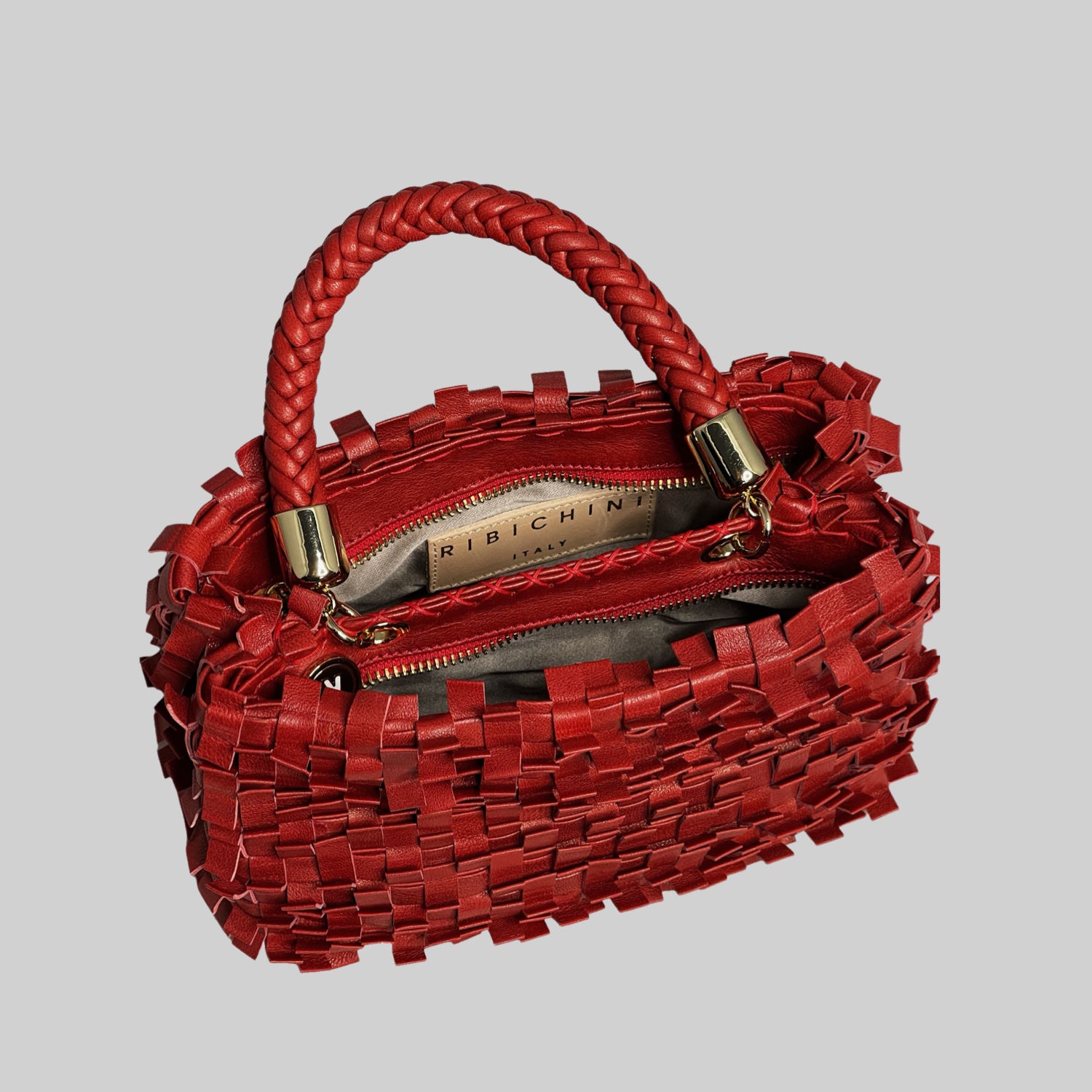 Ribimini-vesken i rødt skinn har et detaljrikt flettemønster og gullfarget glidelås for et elegant utseende.