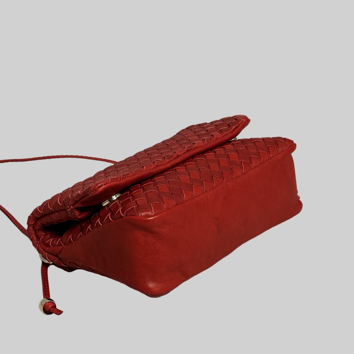 Underside av Ribichini Undercover veske i rødt: Flettet skinn med kontrastfylt, ensfarget base og detaljert fletting.